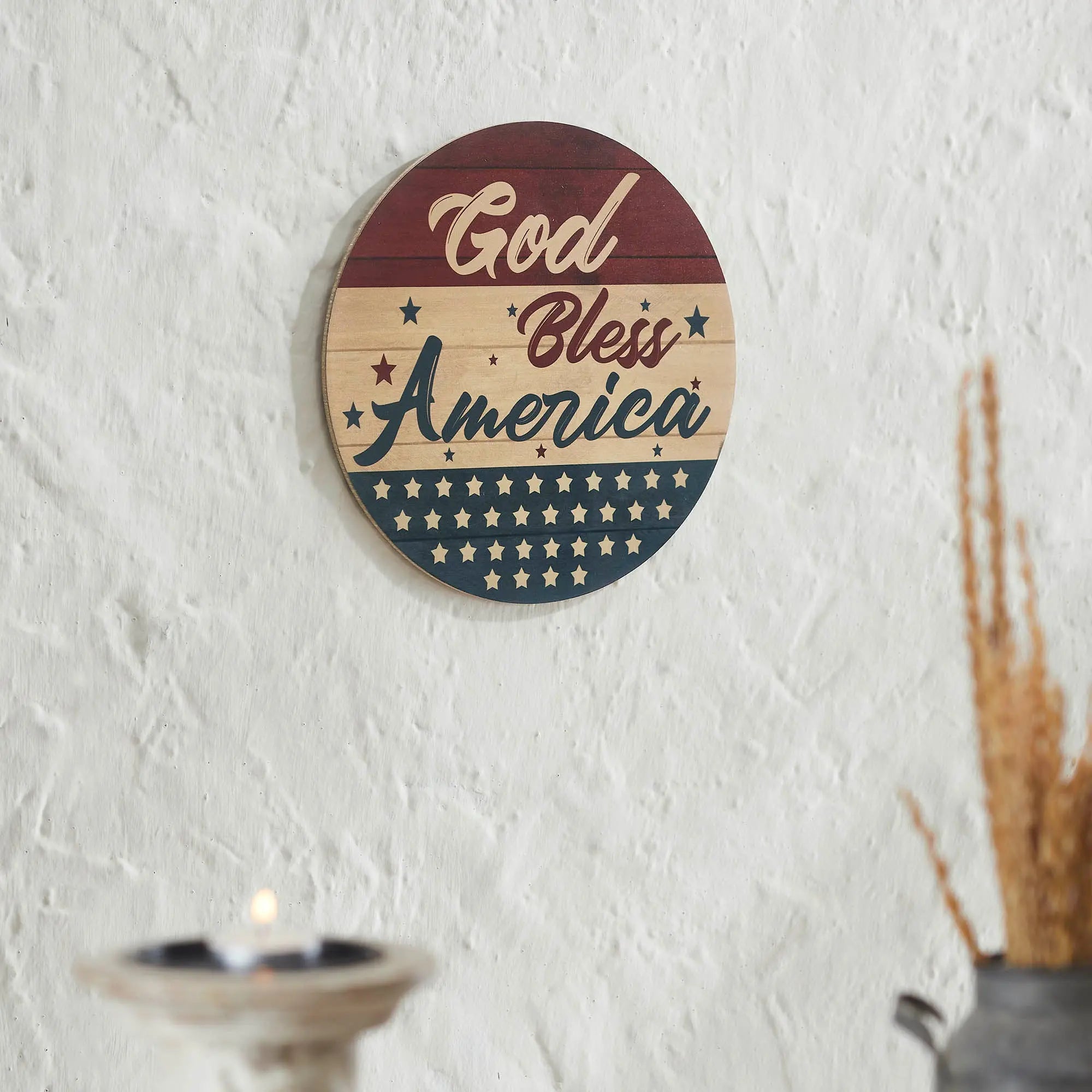 Decorative wall plate with 'God Bless America' text on a white wall.
