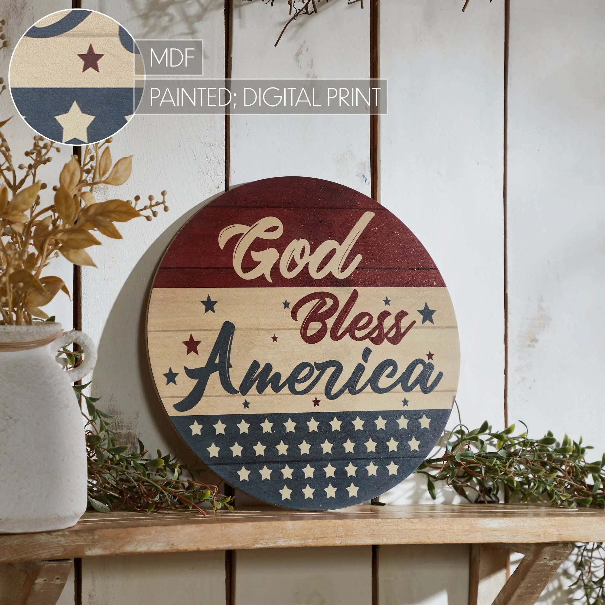 Decorative round sign with 'God Bless America' text on a wooden surface with plants.