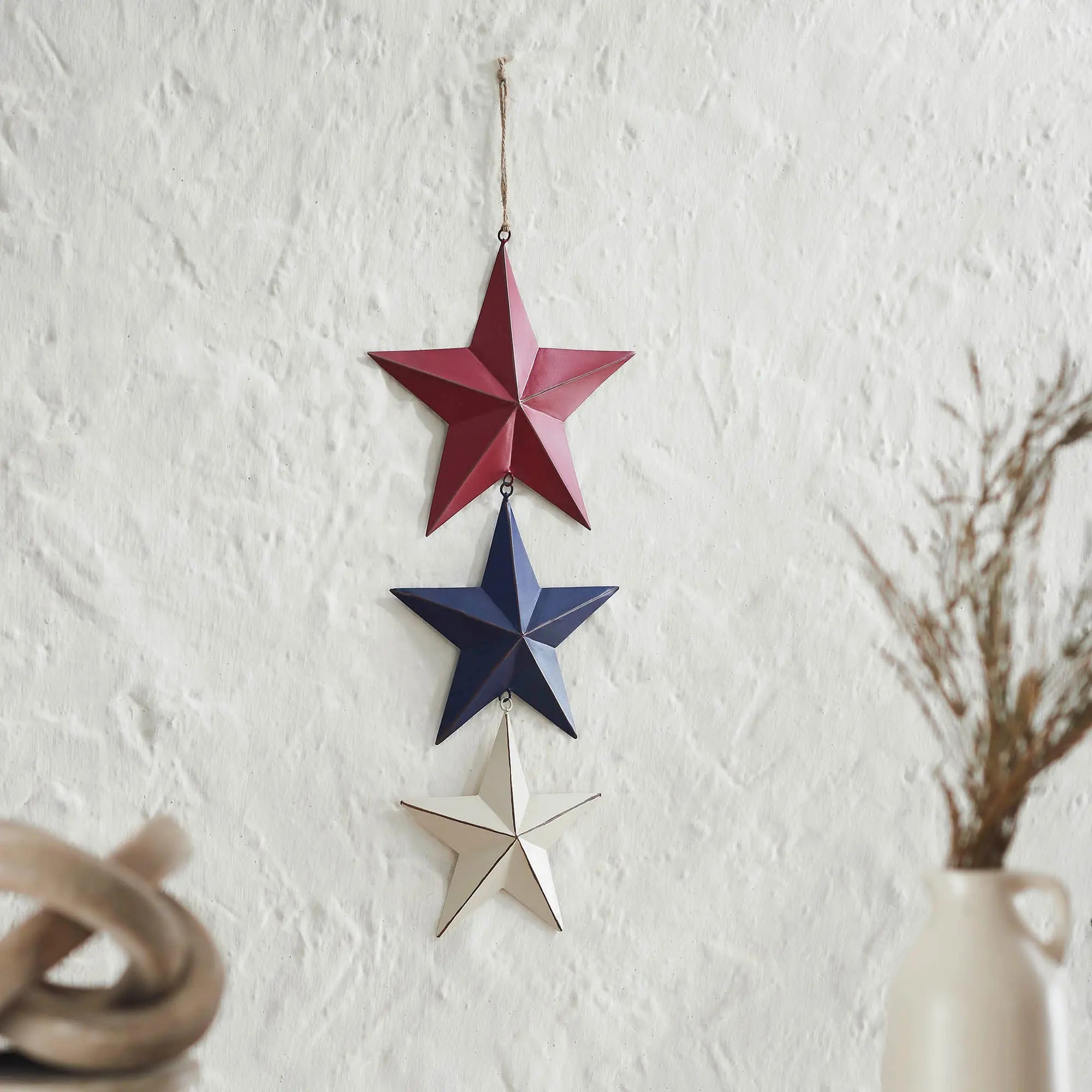 Three star-shaped decorations hanging on a white wall.