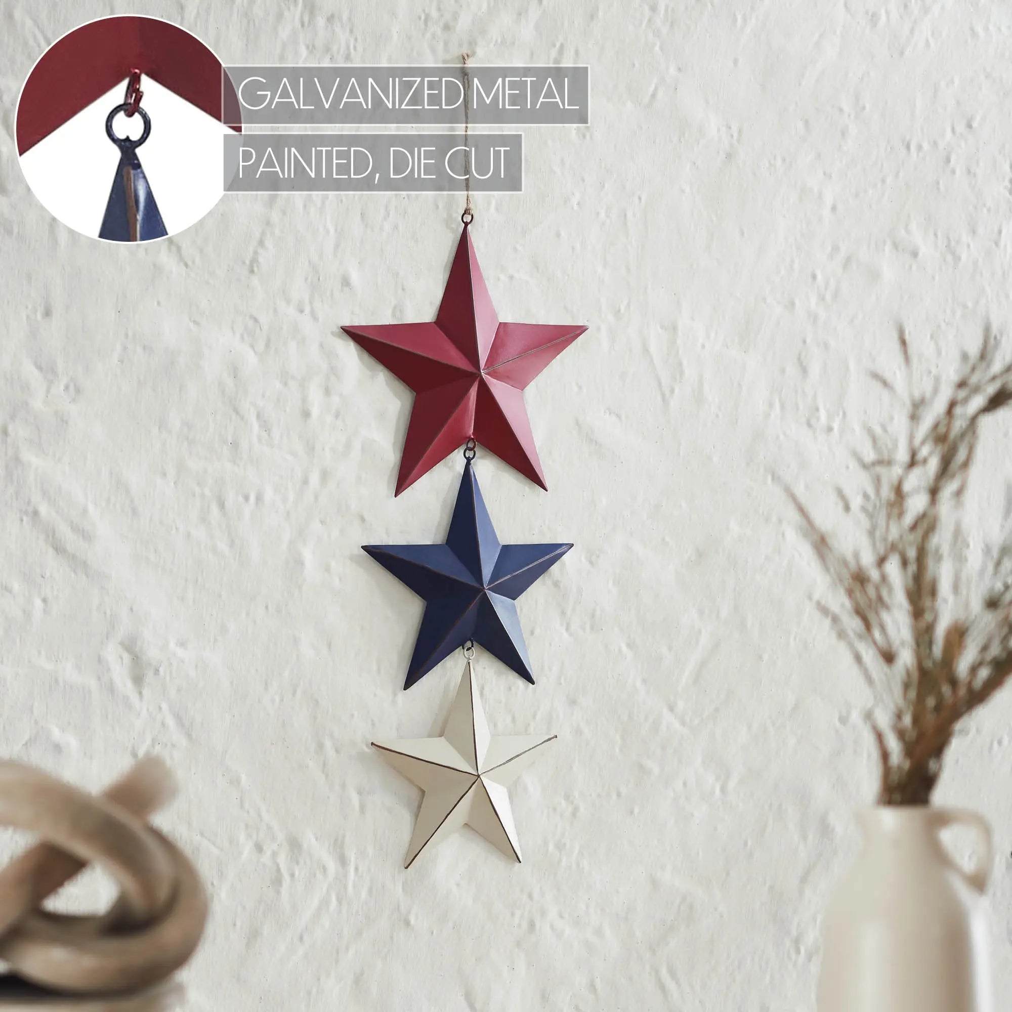 Decorative hanging stars in red, blue, and silver on a white wall.