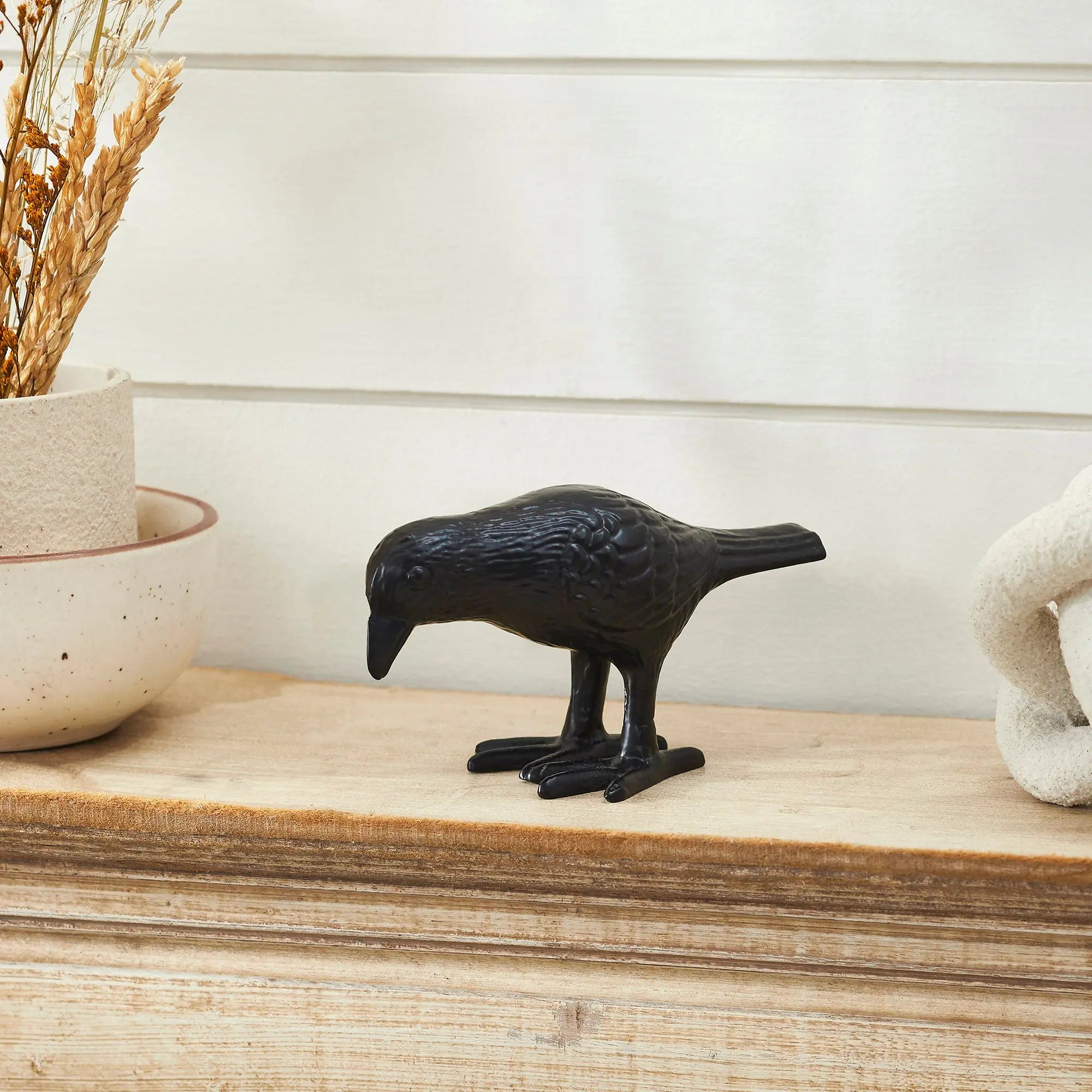 Black bird figurine on a wooden surface with a neutral background