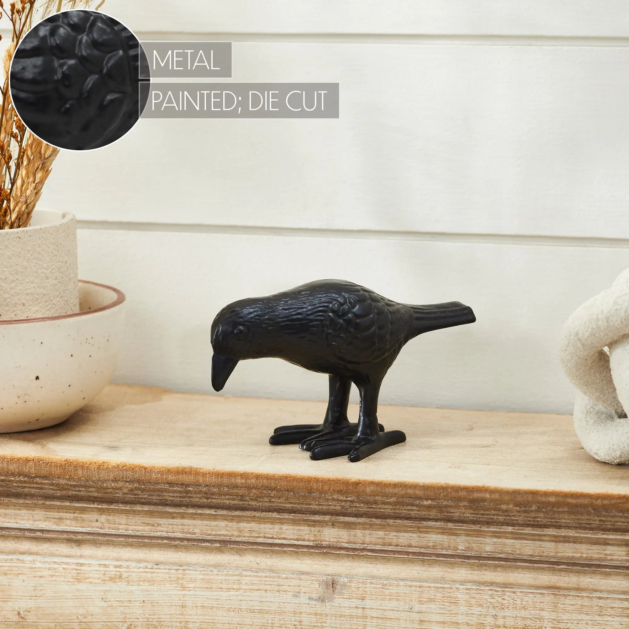 Black metal bird figurine on a wooden surface with a neutral background