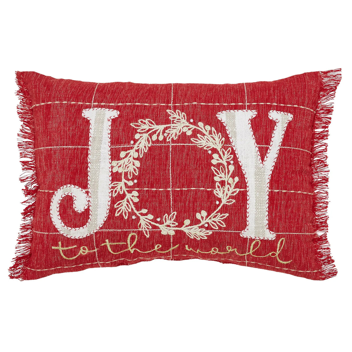 A rectangular red throw pillow with fringe edges, featuring white embroidered lettering that spells 'JOY' with a wreath motif and the phrase 'to the world' in gold script below.