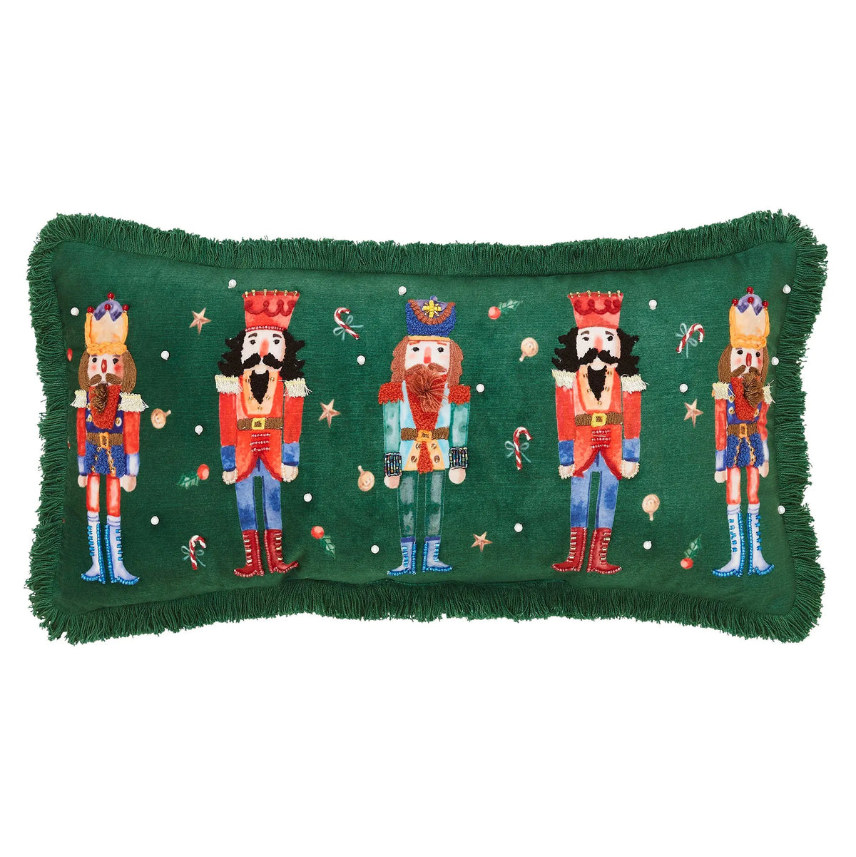 A rectangular green throw pillow with fringe edges, featuring embroidered nutcracker figures and holiday motifs including stars, candy canes, and ornaments on a white background.