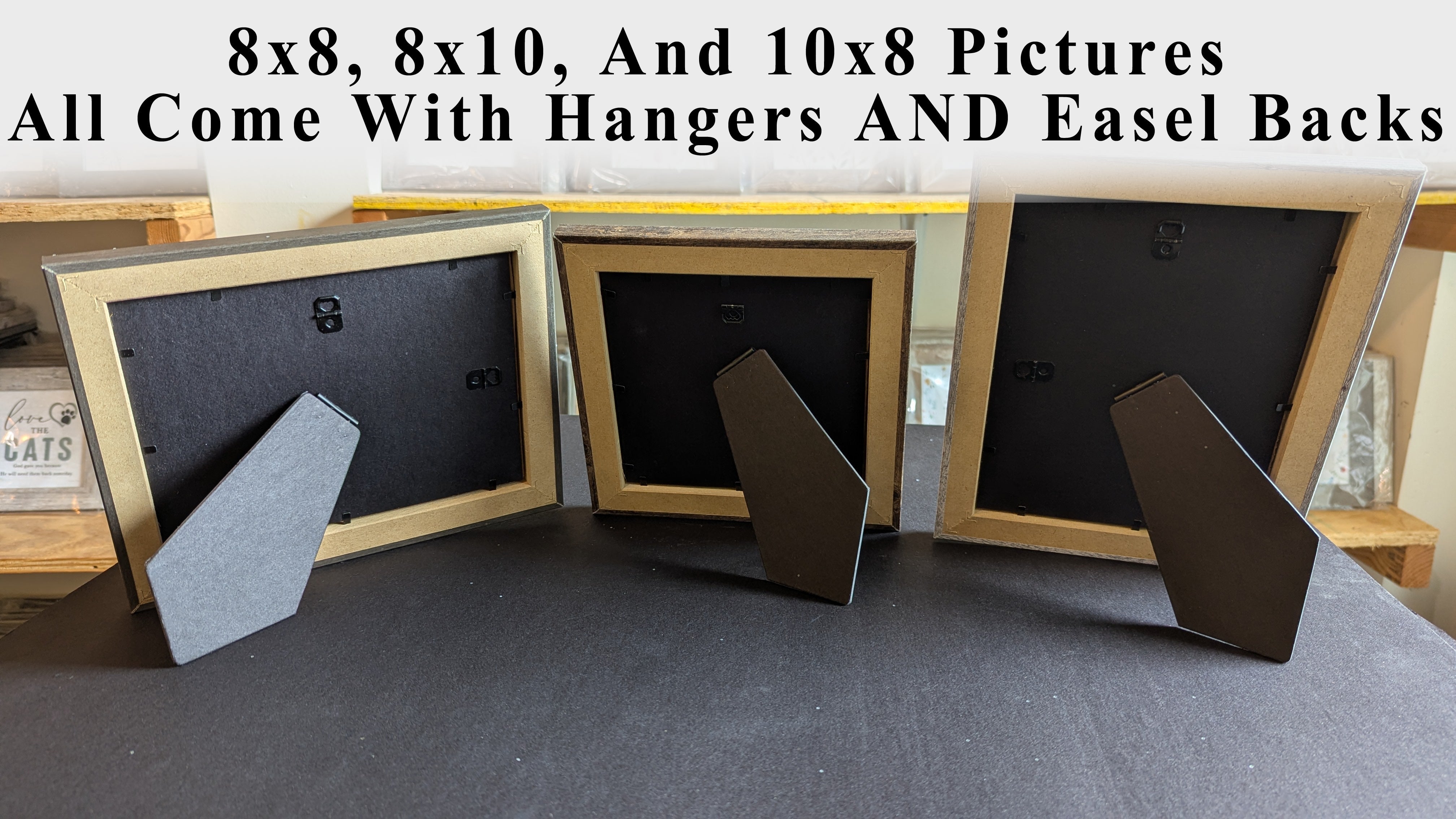 Three picture frames with hangers and easel backs on a gray surface.
