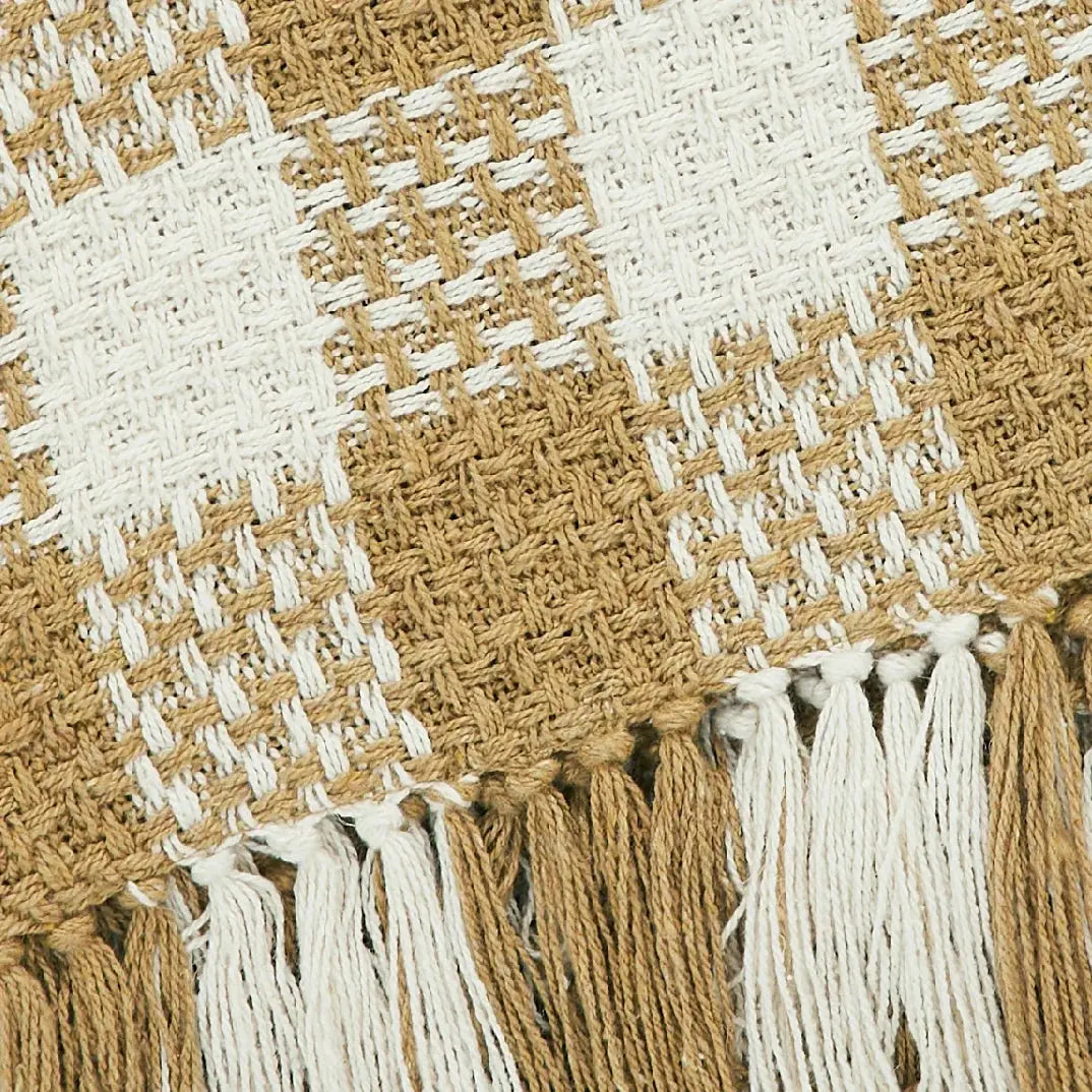 Close-up of a woven blanket with tassels in brown and white plaid pattern