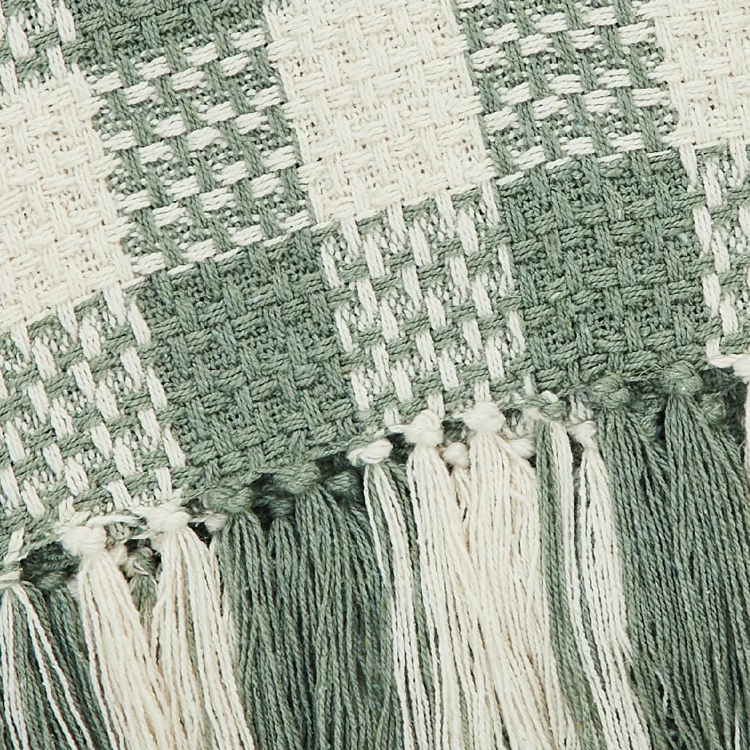 Close-up of woven fabric with tassels in green and white.
