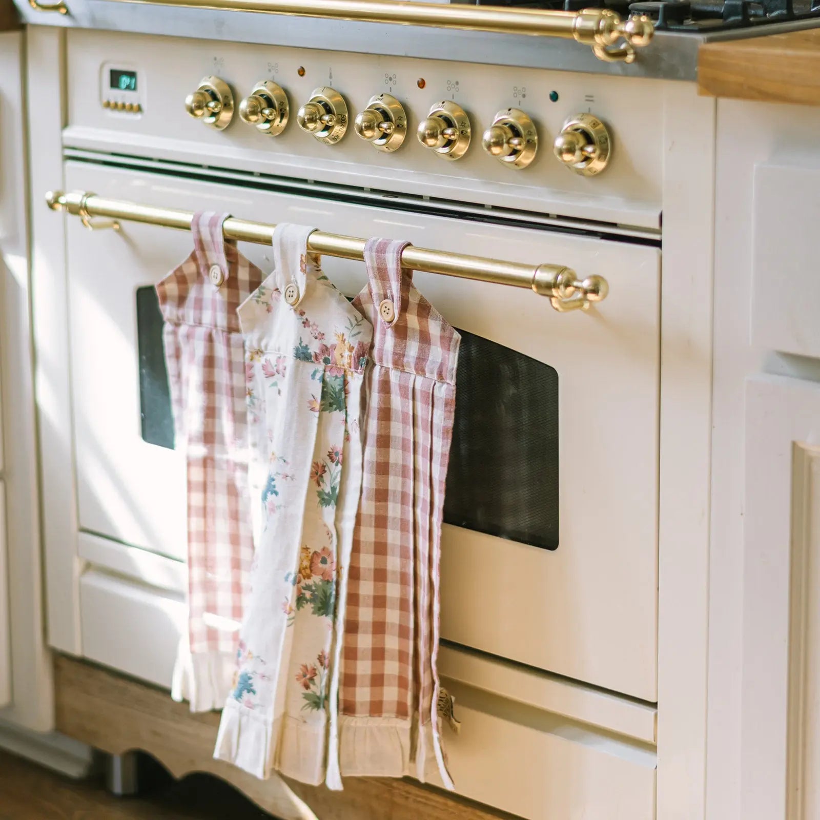 Vintage-style kitchen stove with checkered towels hanging on a gold handle.