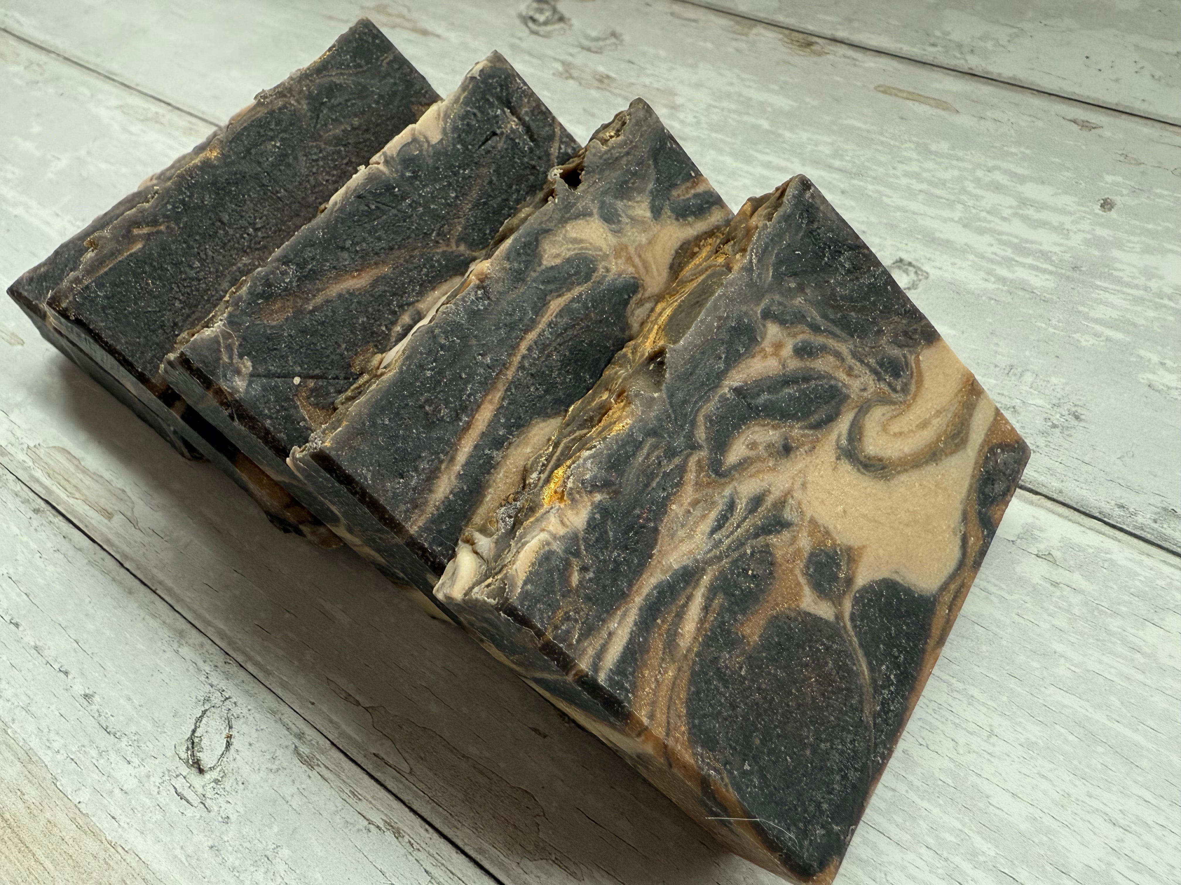 Three bars of soap with a marbled design on a wooden surface