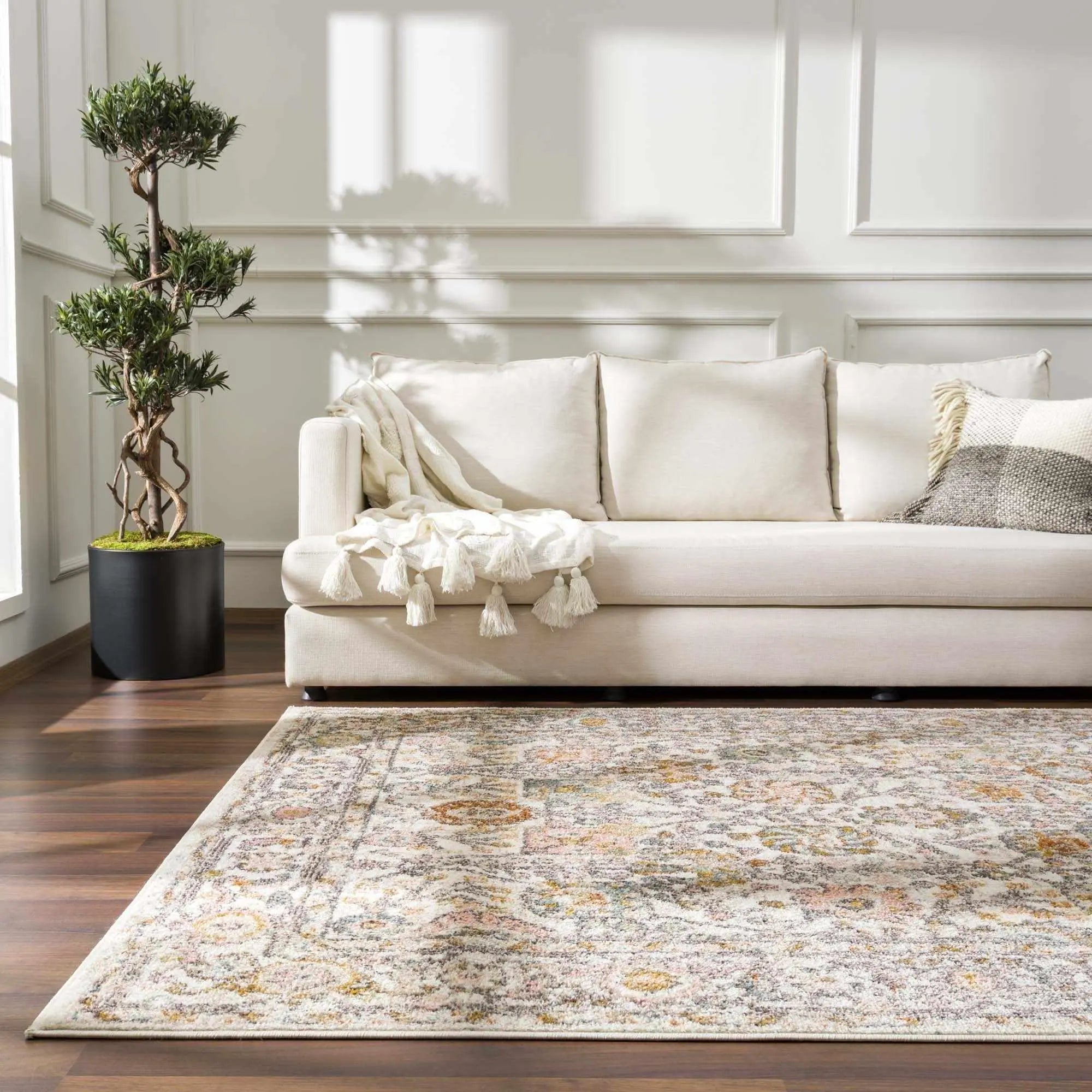 Cozy farmhouse living room with cream sofa, tassel throw, and vintage-style area rug