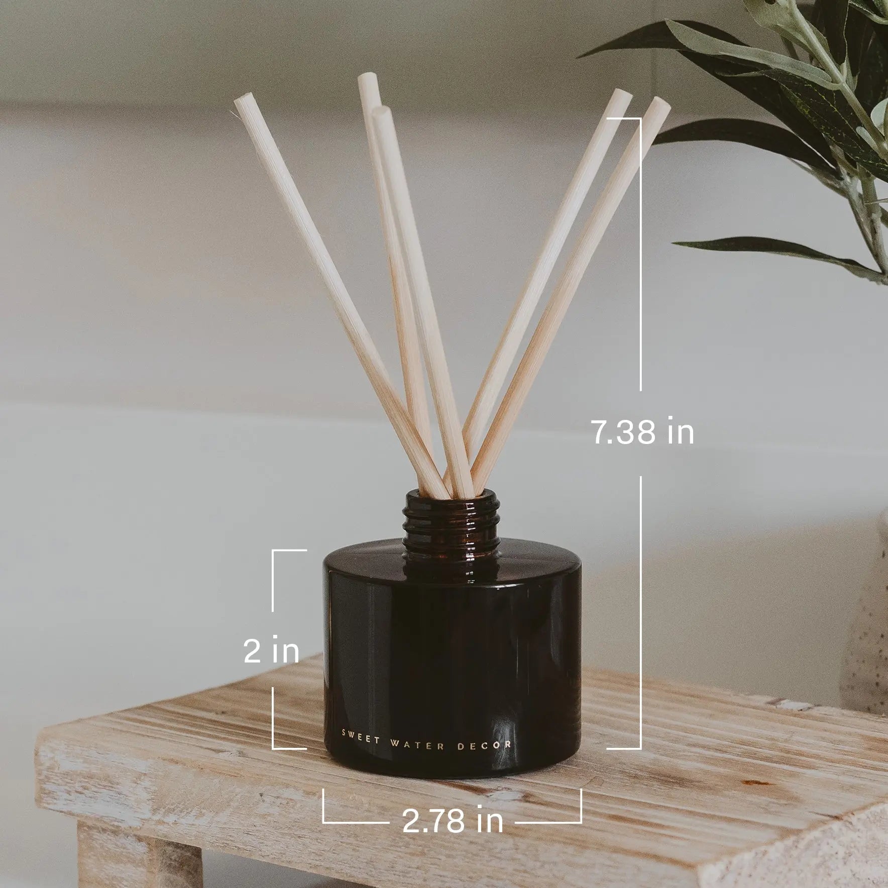 Black diffuser with wooden sticks on a wooden surface, with measurements indicated.