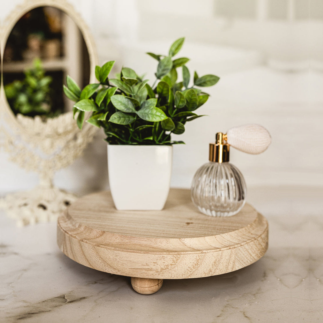 Small wooden table with a potted plant and a glass bottle on a marble surface.