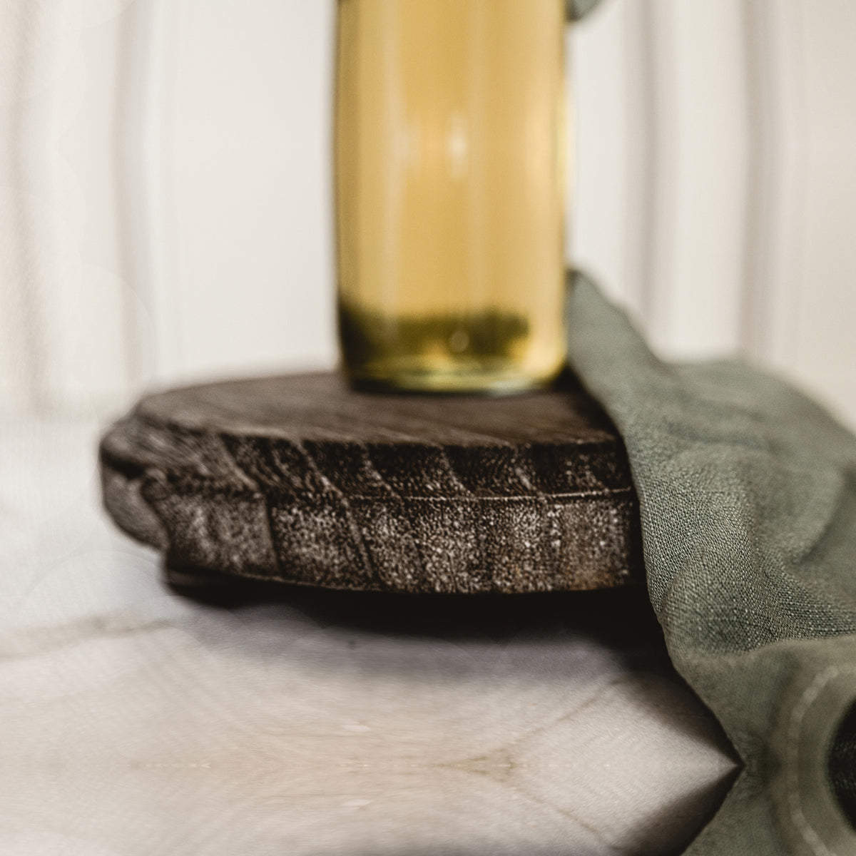 Close-up of a glass of beer on a textured coaster with a green cloth in the background.