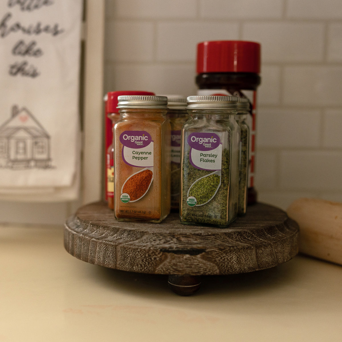 Spice jars on a wooden turntable with a tiled wall background
