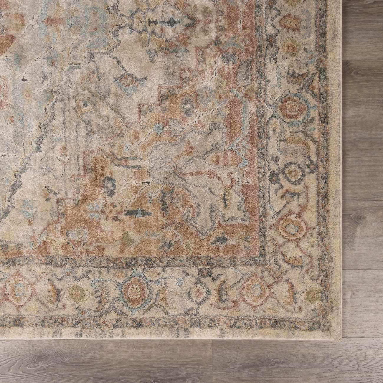 Vintage-style area rug with distressed floral pattern in beige, blue, and rust tones on wood floor