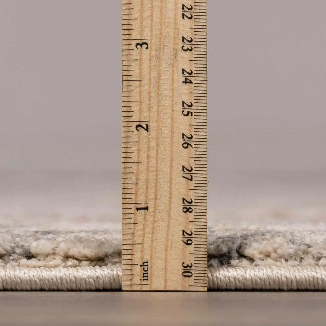Cozy farmhouse rug thickness measured with wooden ruler, soft textured weave for warm home decor