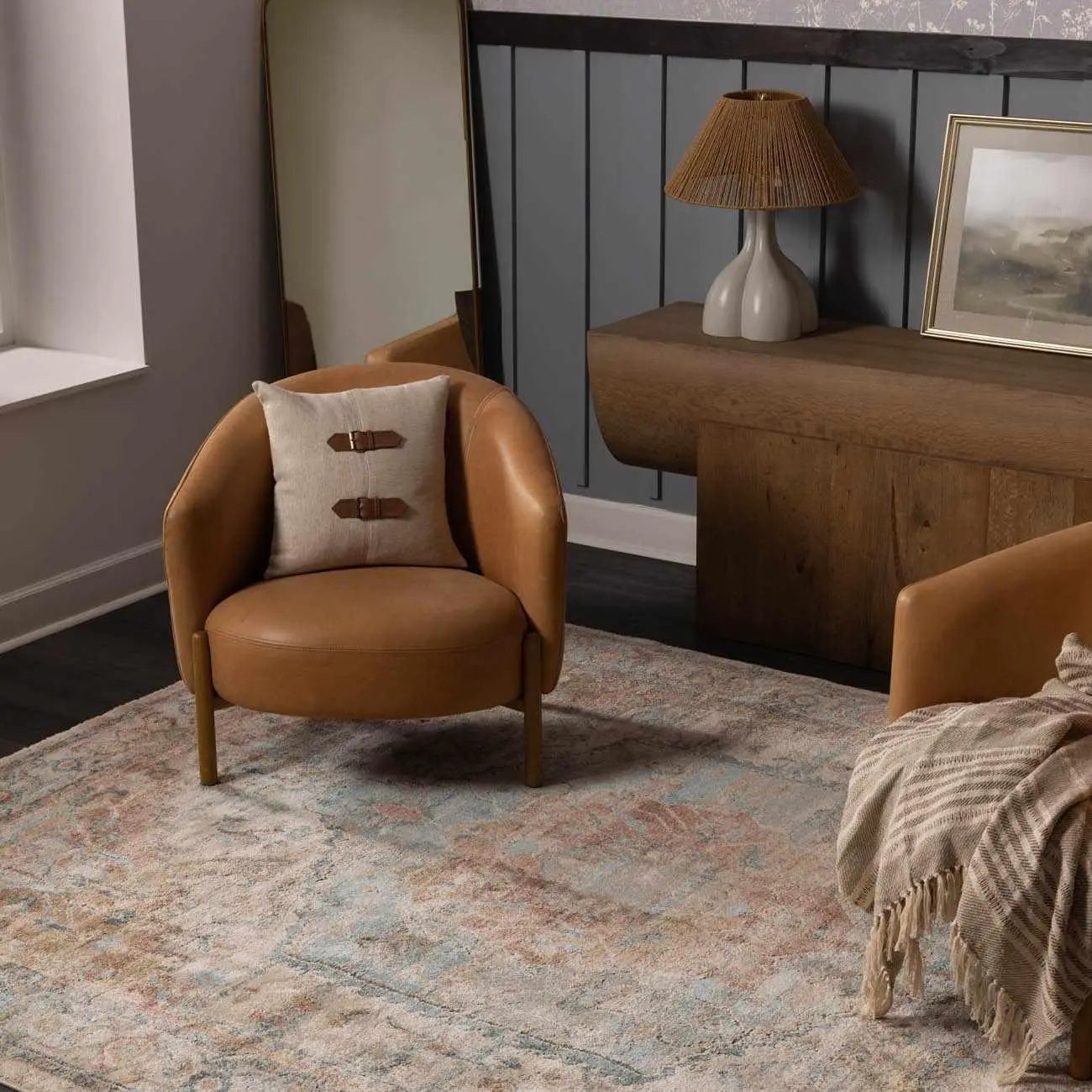 Cozy tan leather armchair with buckle pillow, rustic wood console, and vintage rug in farmhouse living room