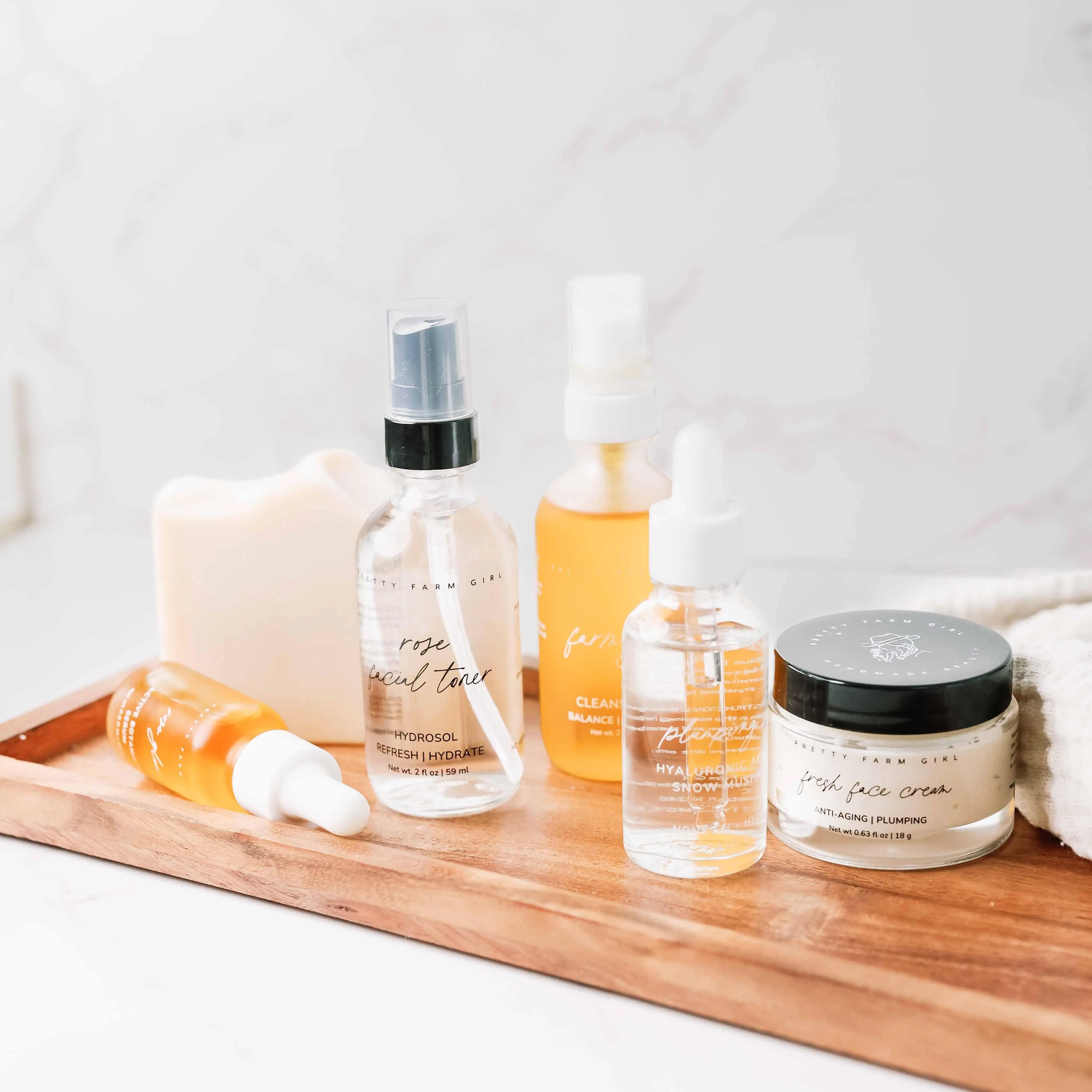 Pretty Farm Girl skincare set with rose toner, face cream, and serums on wooden tray for cozy bath essentials