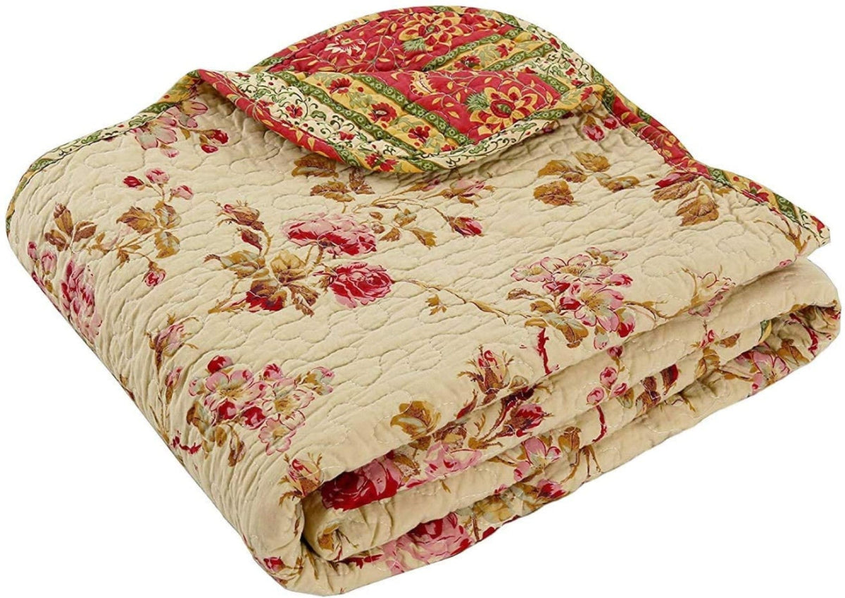 A folded quilted cotton blanket with a vintage floral pattern in red, pink, and green on a cream background, shown against a plain white background.