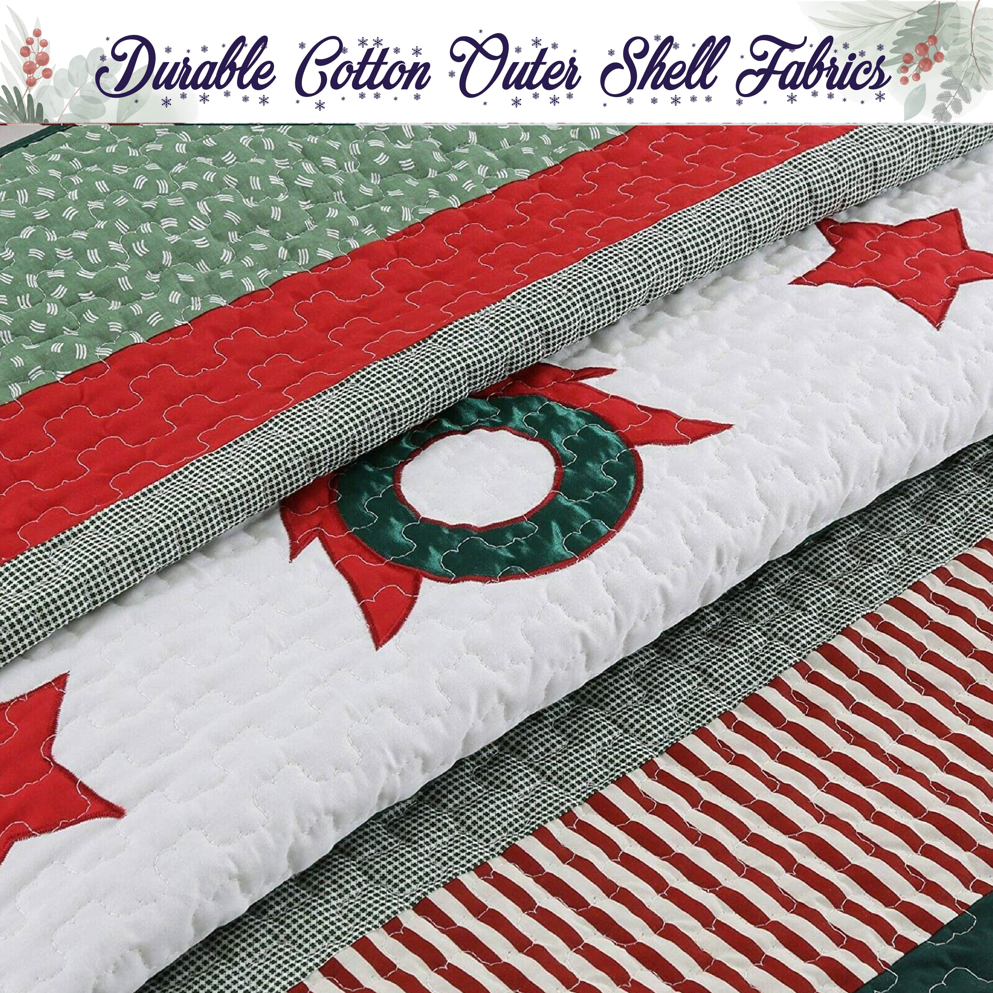 A close-up of folded quilted fabric with a holiday-themed pattern, including red stars, a green wreath motif, red and white stripes, and a green-and-white gingham border. A banner at the top reads 'Durable Cotton Outer Shell Fabrics'.