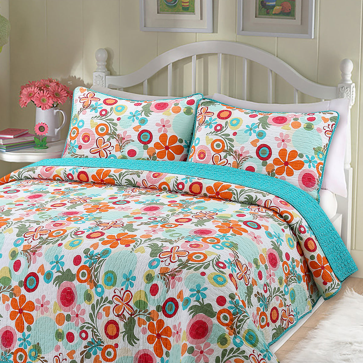 A colorful floral bedding set with a quilt and two matching pillowcases, styled on a bed with a white wooden headboard in a bedroom setting.