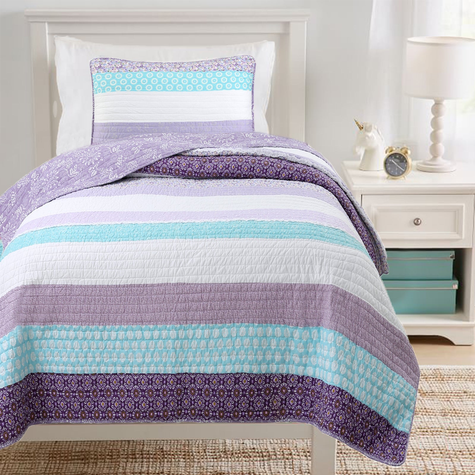 Striped purple and blue quilt set on a bed in a bedroom setting.