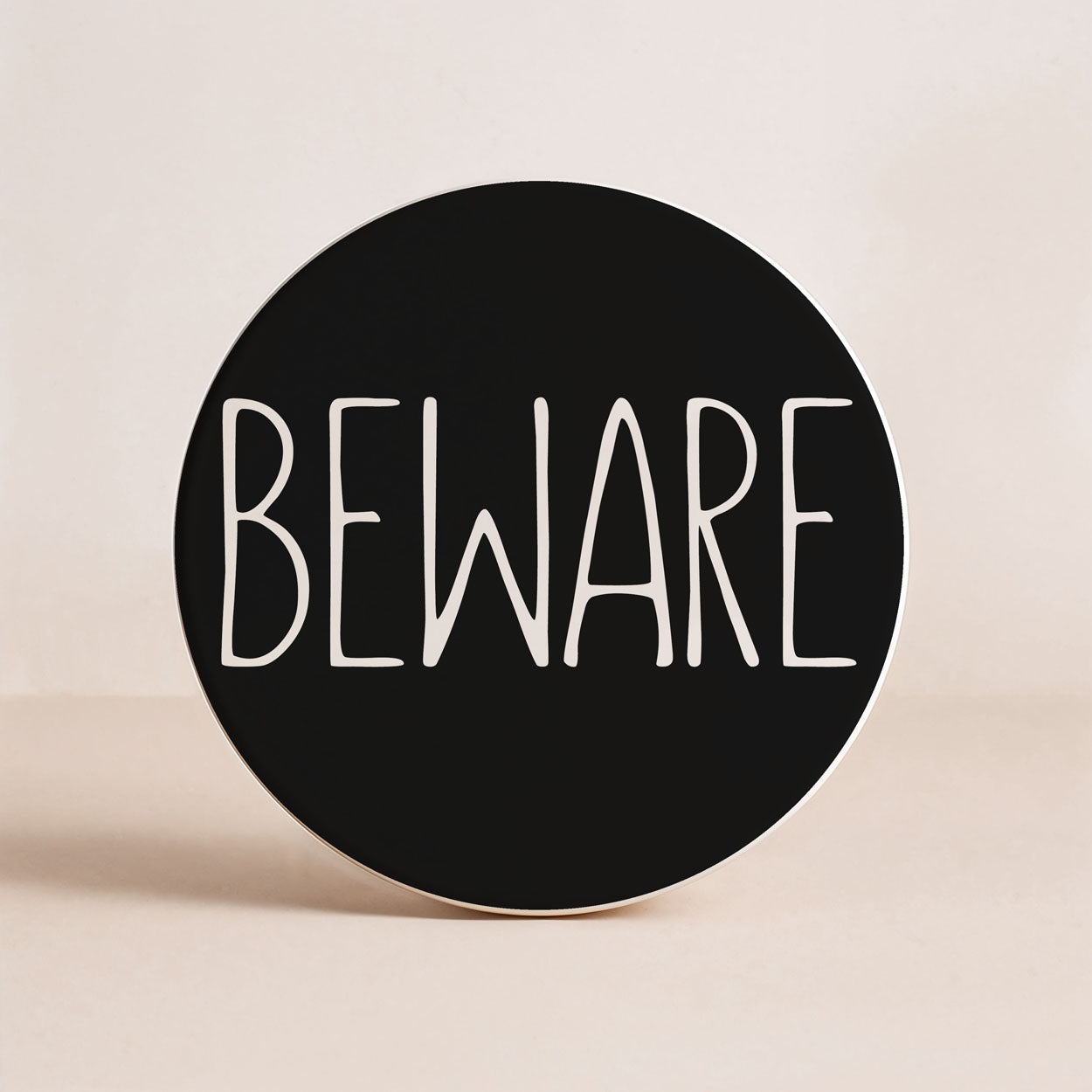 Round black sign with 'BEWARE' text on a beige background