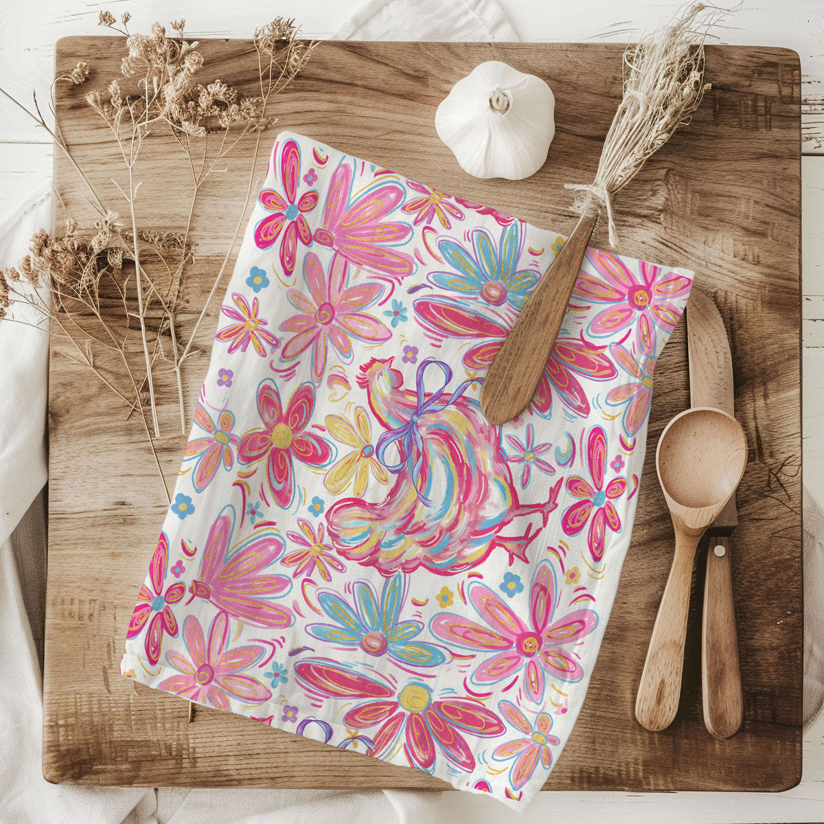Floral-patterned towel on a wooden cutting board with wooden spoons and a white pumpkin.