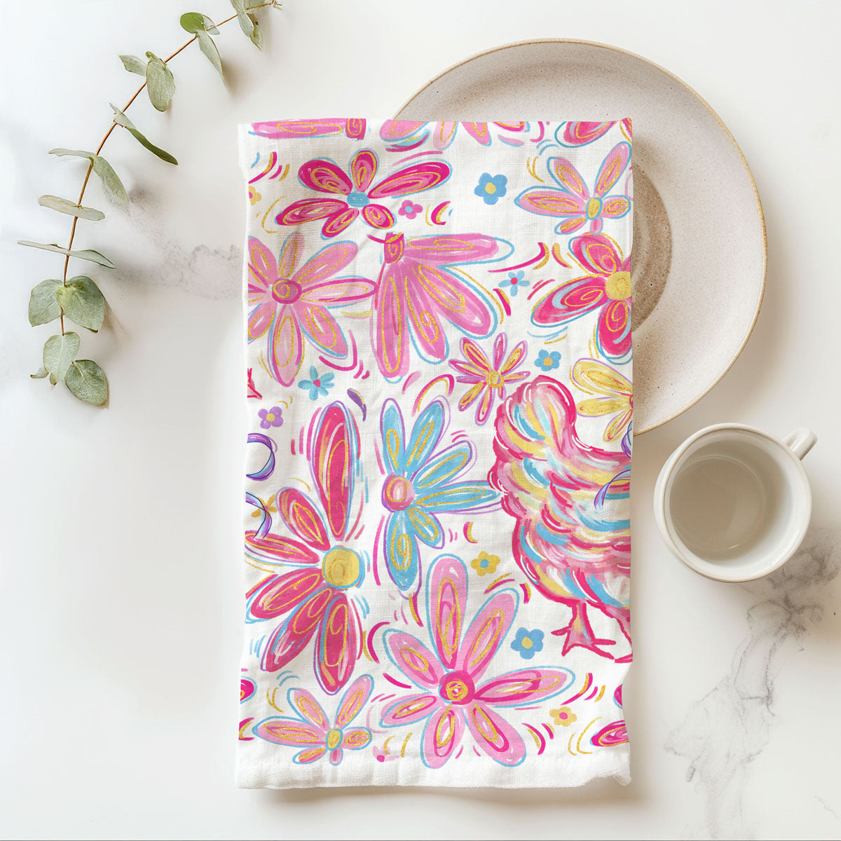 Floral patterned towel on a marble surface with a cup and plant.
