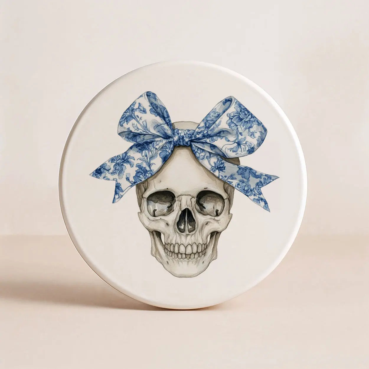 Round object with a skull design and a blue floral bow on a beige background
