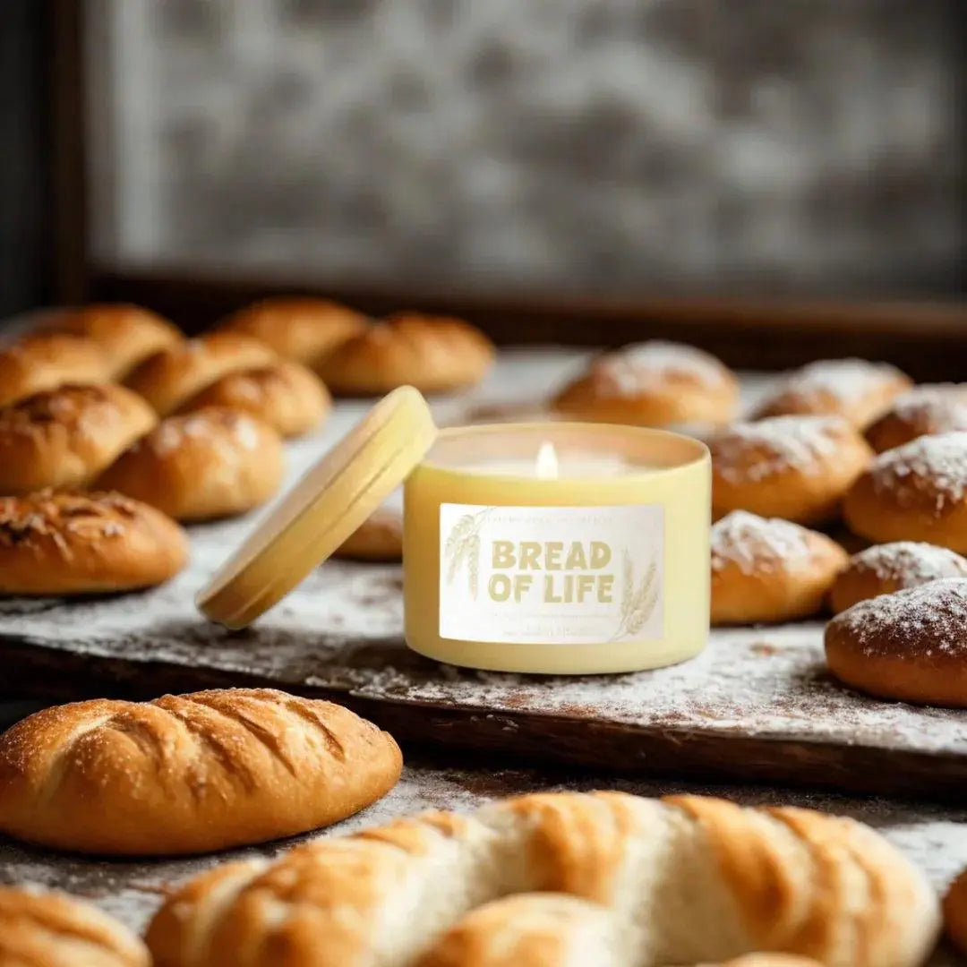 Bread of Life scented candle surrounded by fresh baked bread rolls, cozy farmhouse decor