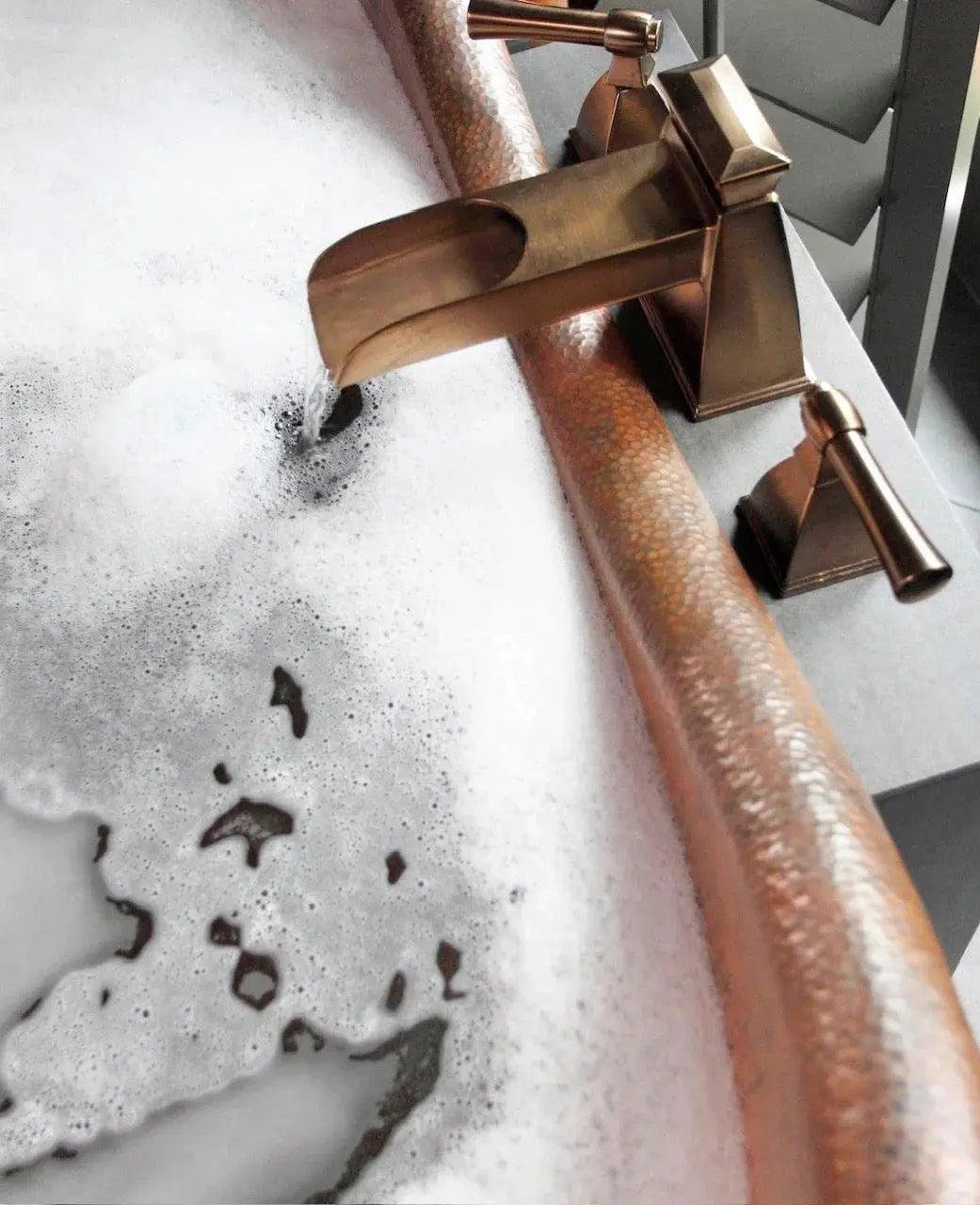Copper farmhouse tub faucet with hammered finish, filling soapy bath for cozy bathroom decor