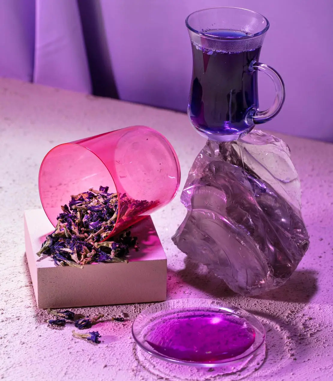 Purple liquid in a glass carafe with lavender flowers on a textured surface