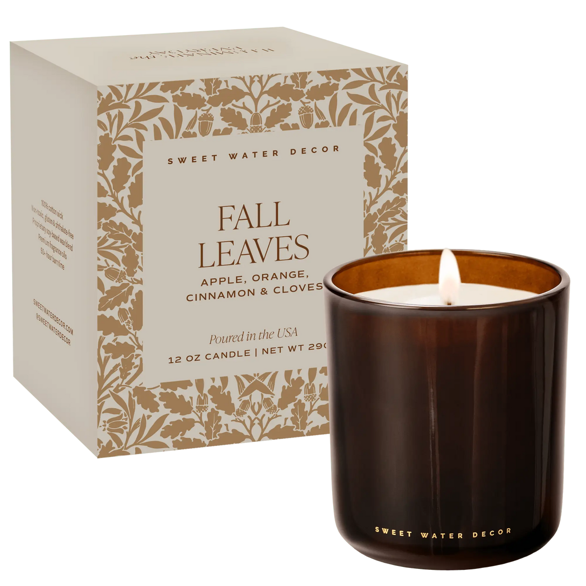A lit 12 oz scented candle in a dark amber glass jar next to its cream-colored packaging box with gold botanical leaf patterns. The box is labeled 'FALL LEAVES' by 'SWEET WATER DECOR'.