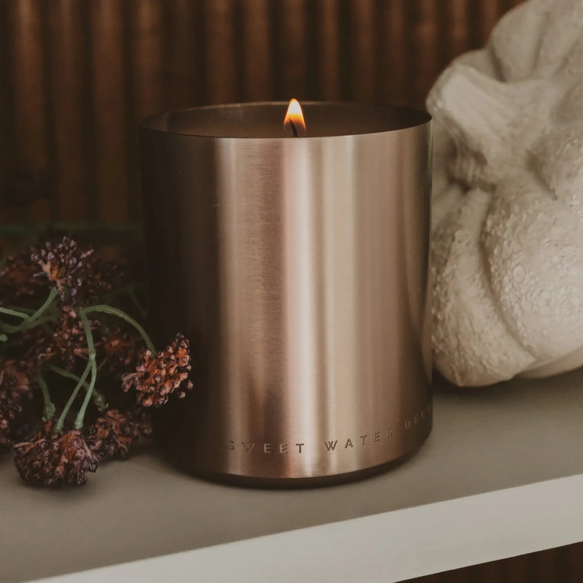 Bronze candle holder with a lit candle on a surface with decorative elements.