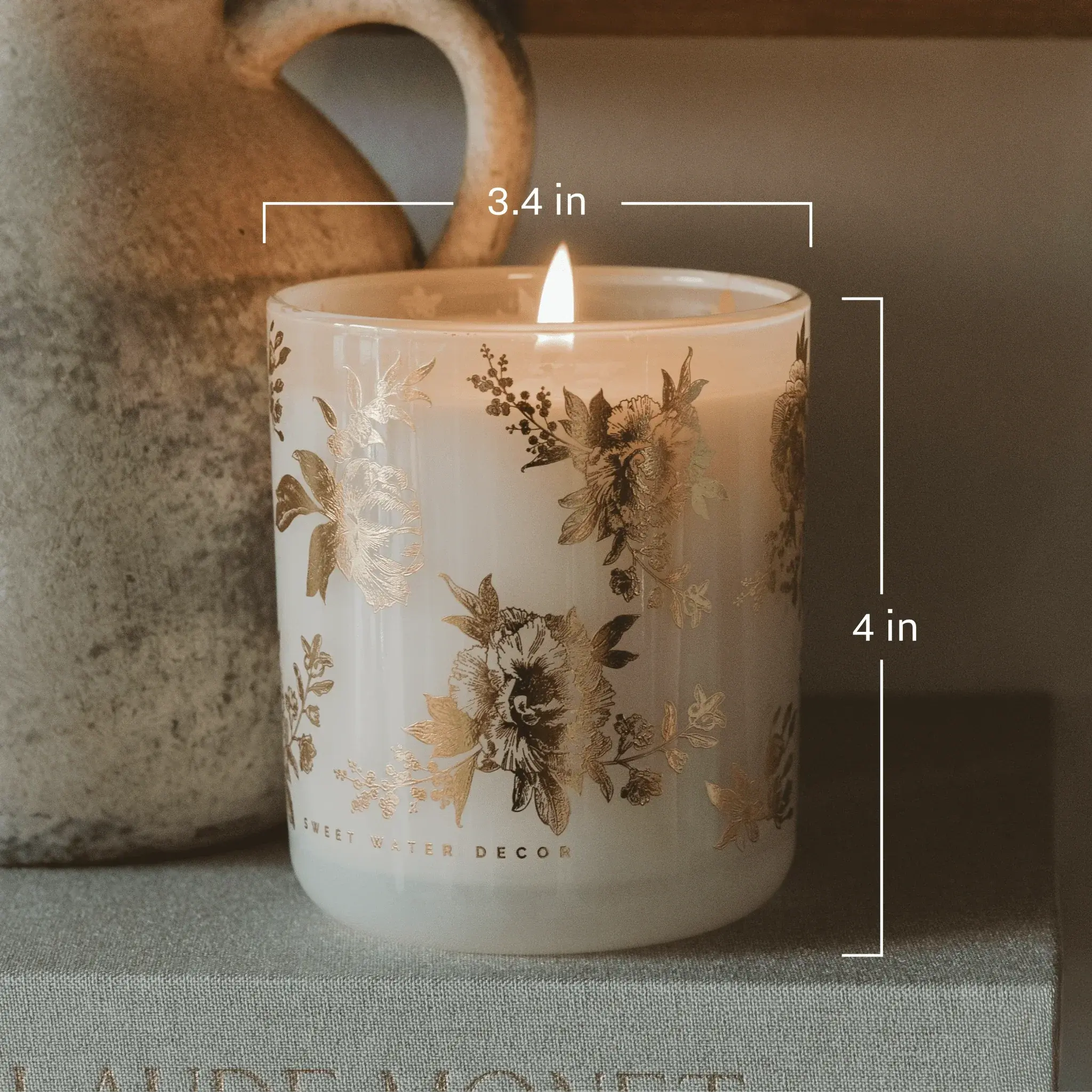 Lit floral candle in frosted glass jar with gold botanical print, cozy farmhouse decor, 4 inches tall
