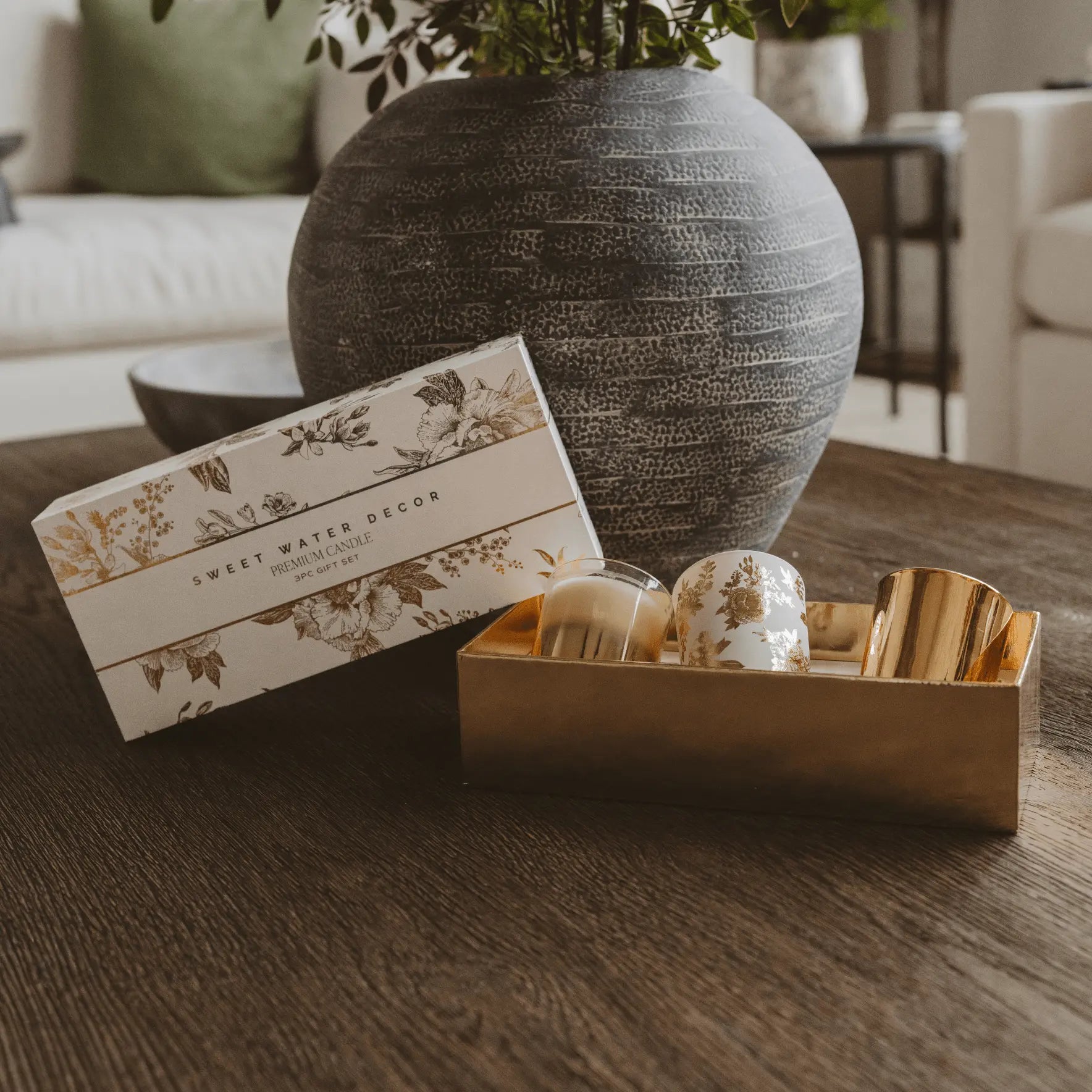 Decorative items including a box labeled 'Sweet Water Decor' and a gold tray with decorative objects on a wooden surface.