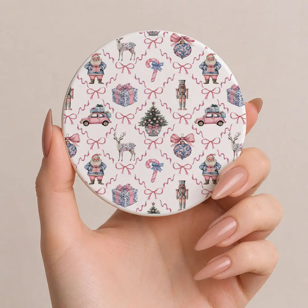 Round compact mirror with festive pattern held by a hand against a beige background