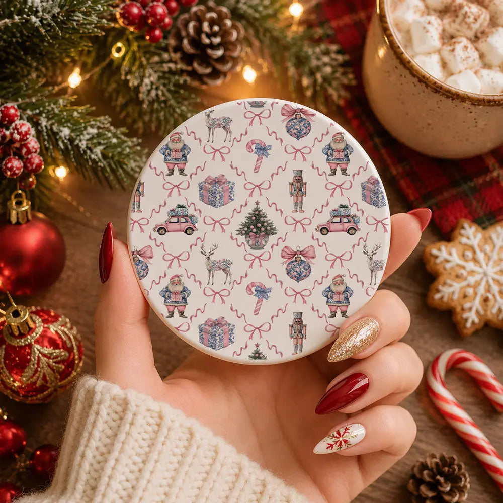 Hand holding a round decorative item with Christmas-themed pattern, surrounded by festive items like cookies and a mug.