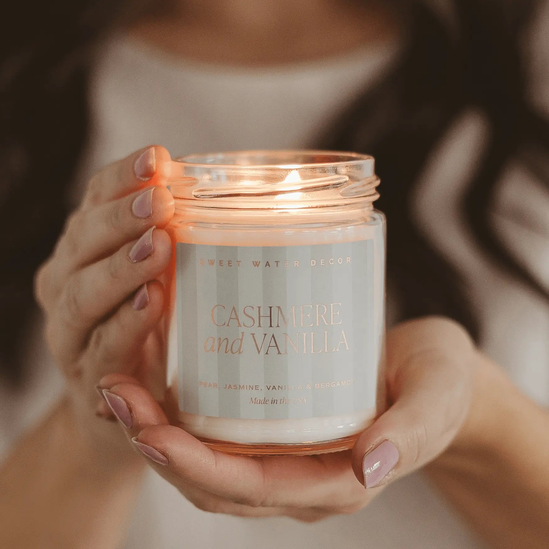 Cashmere and Vanilla scented candle in glass jar, held gently for cozy home decor ambiance