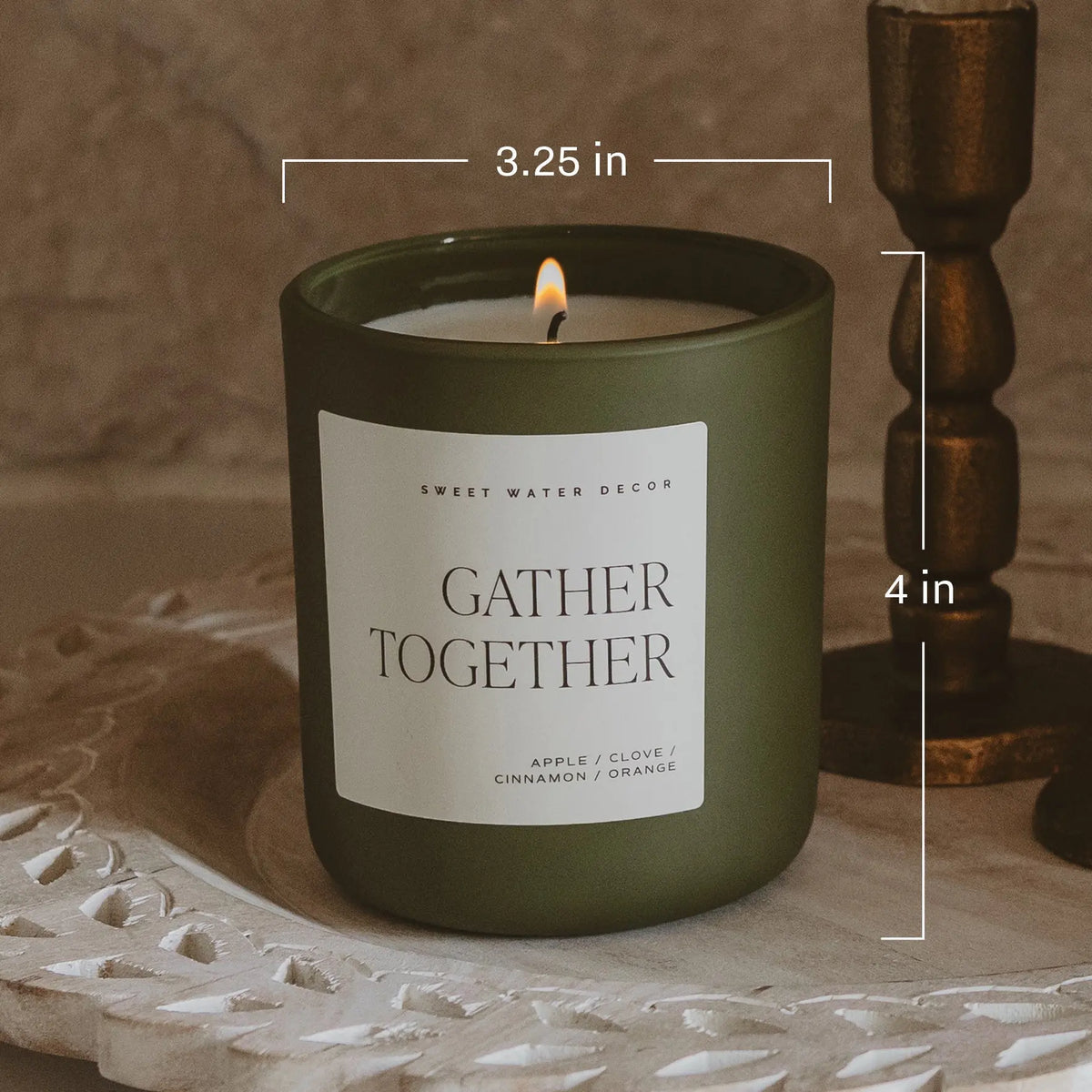Green candle labeled 'Gather Together' with measurements on a textured surface.