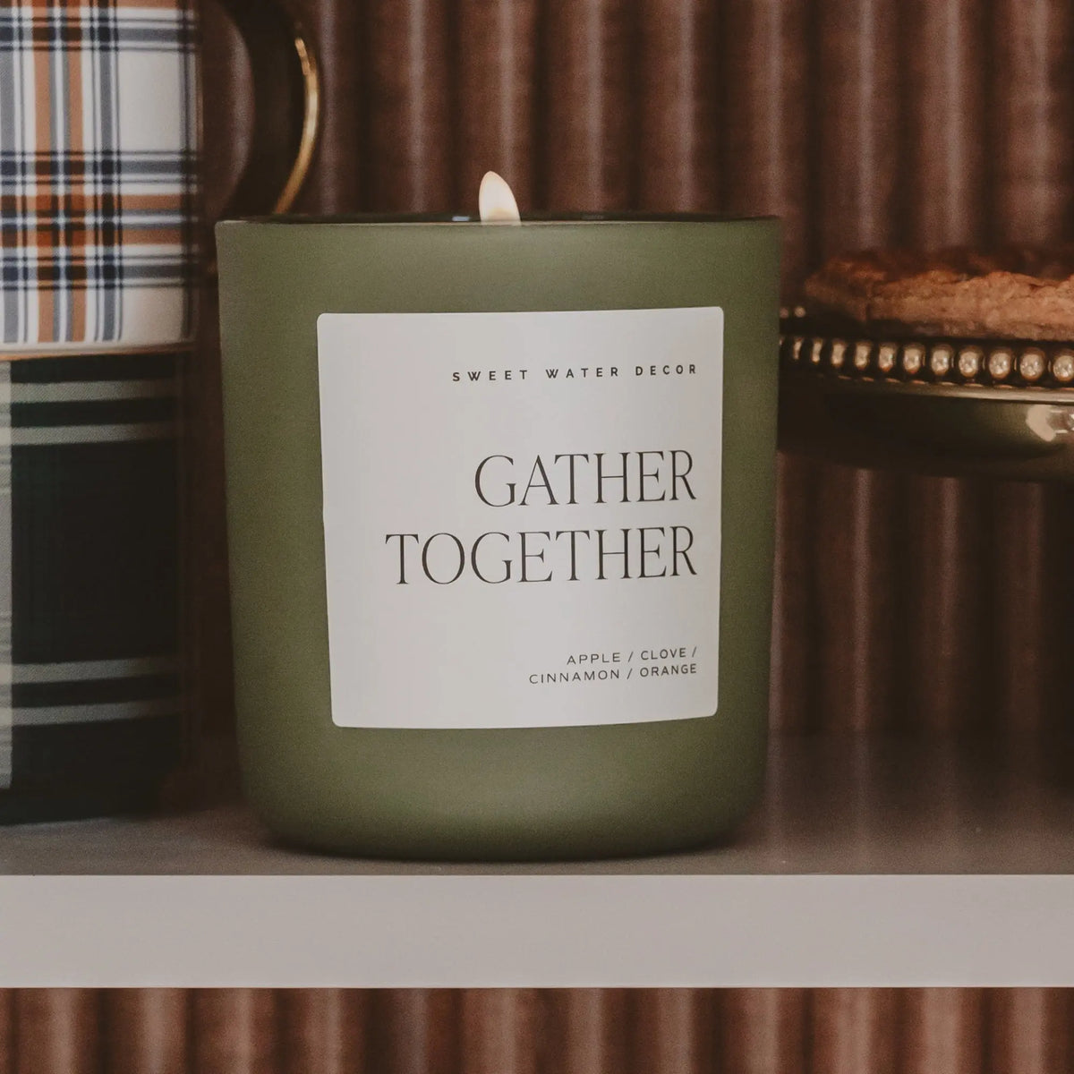 Green candle with 'Gather Together' label on a wooden surface