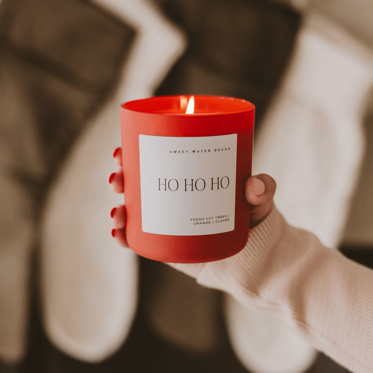 Person holding a red candle labeled 'HO HO HO' with a blurred background