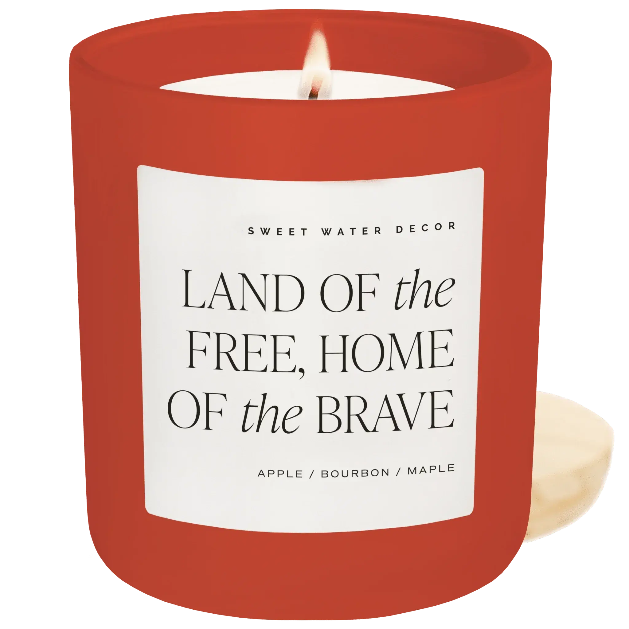 Red candle with a white label featuring text and branding on a green background