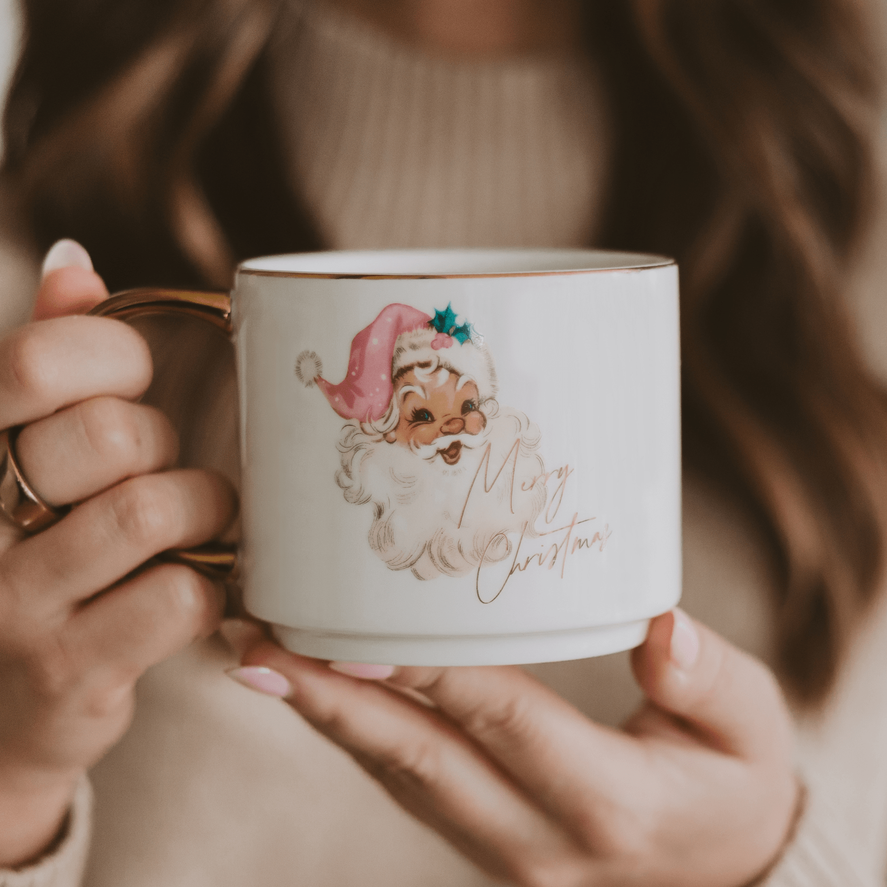 Person holding a Christmas-themed mug with a cartoon Santa Claus design.