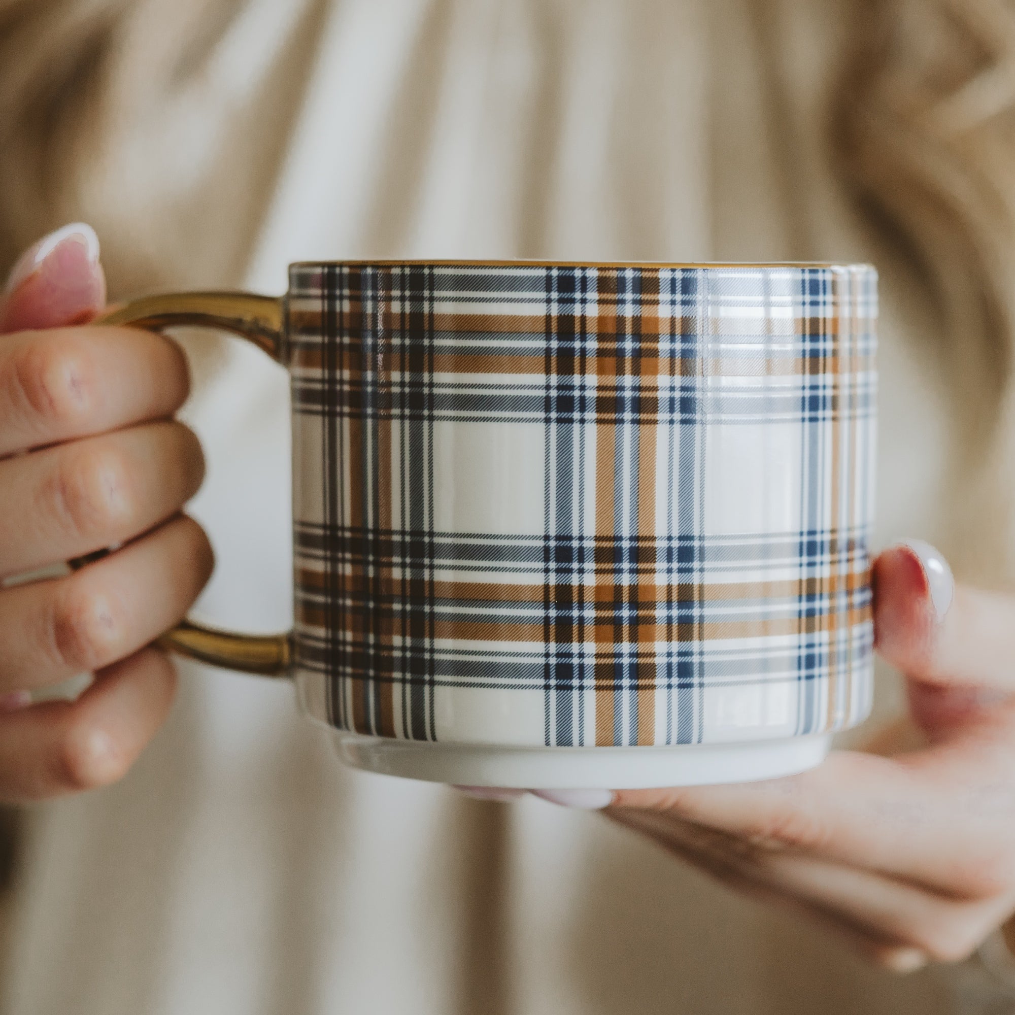 Person holding a plaid-patterned mug with a blurred background