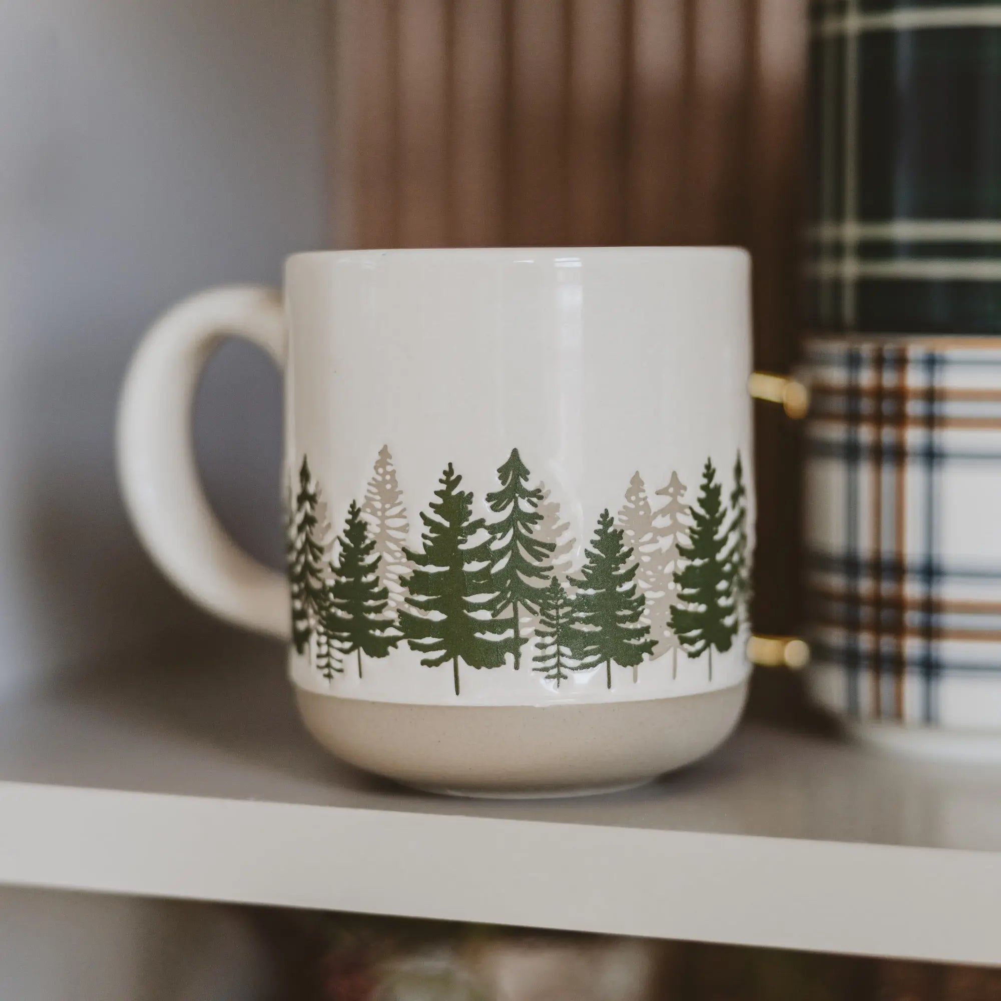 White mug with green tree pattern on a shelf