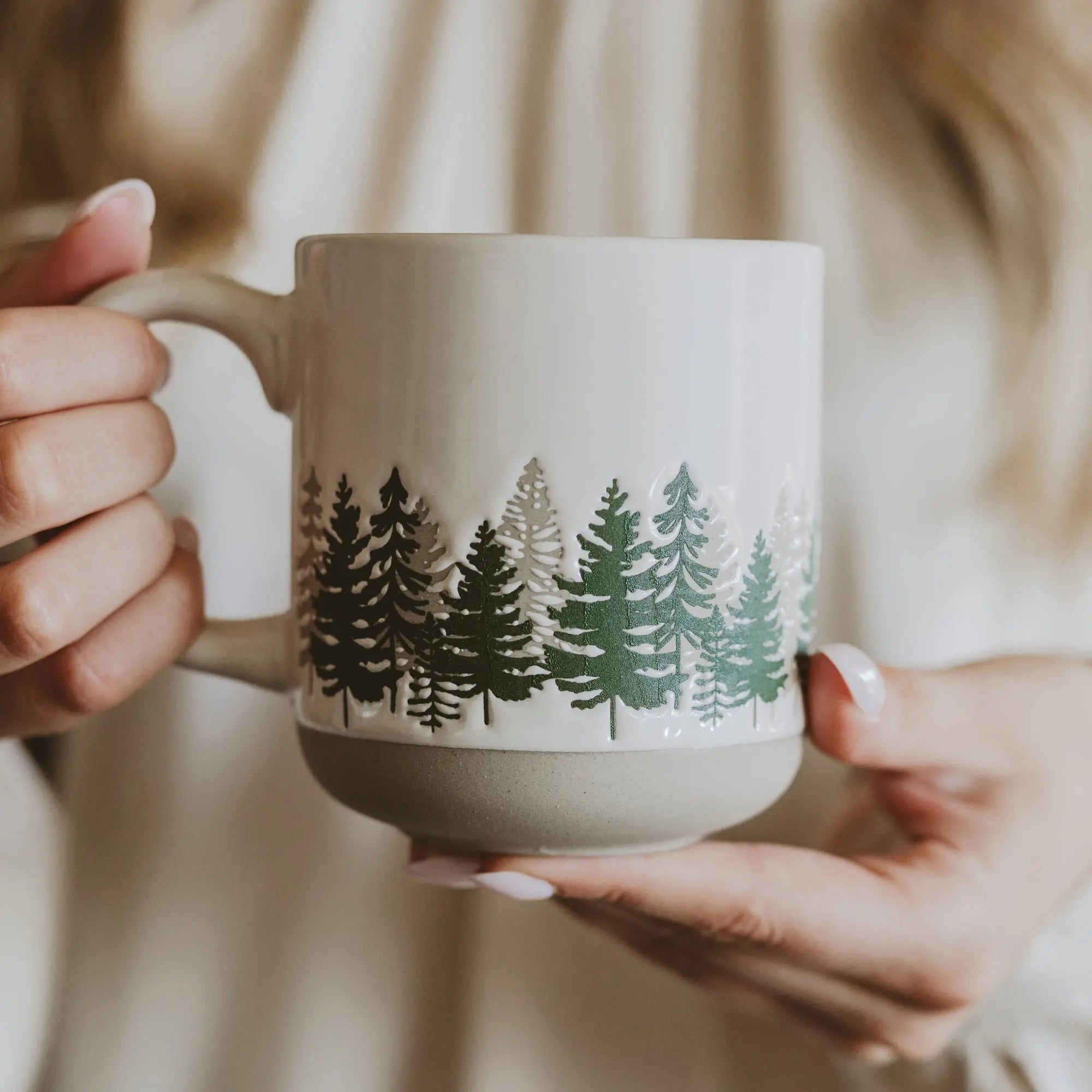 Person holding a mug with forest design