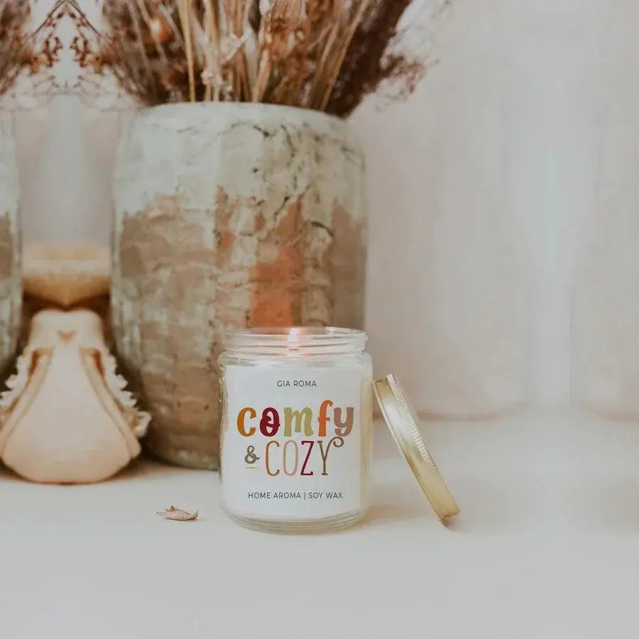 Candle labeled 'comfy & cozy' with decorative items in the background