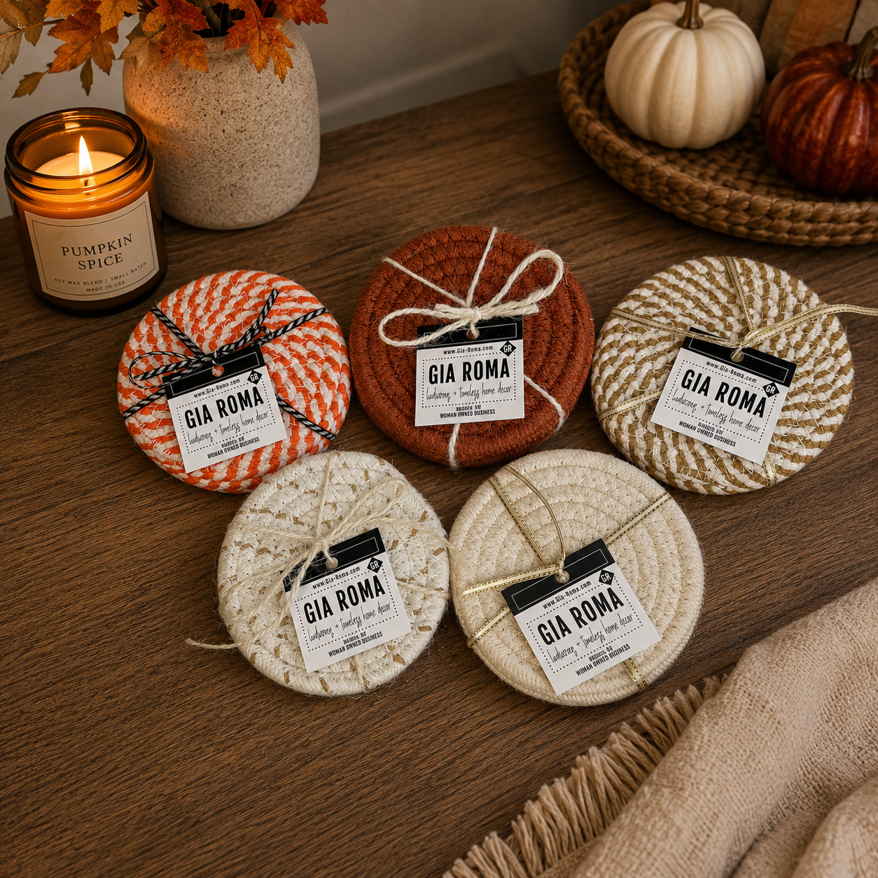 Set of Gia Roma coasters on a wooden surface with pumpkins and a candle in the background.